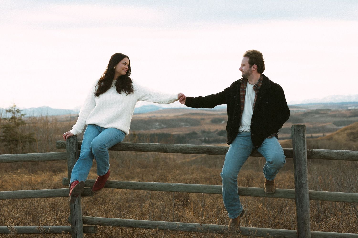 Two people practicing martial arts or dance moves in an outdoor field with mountains in the background.