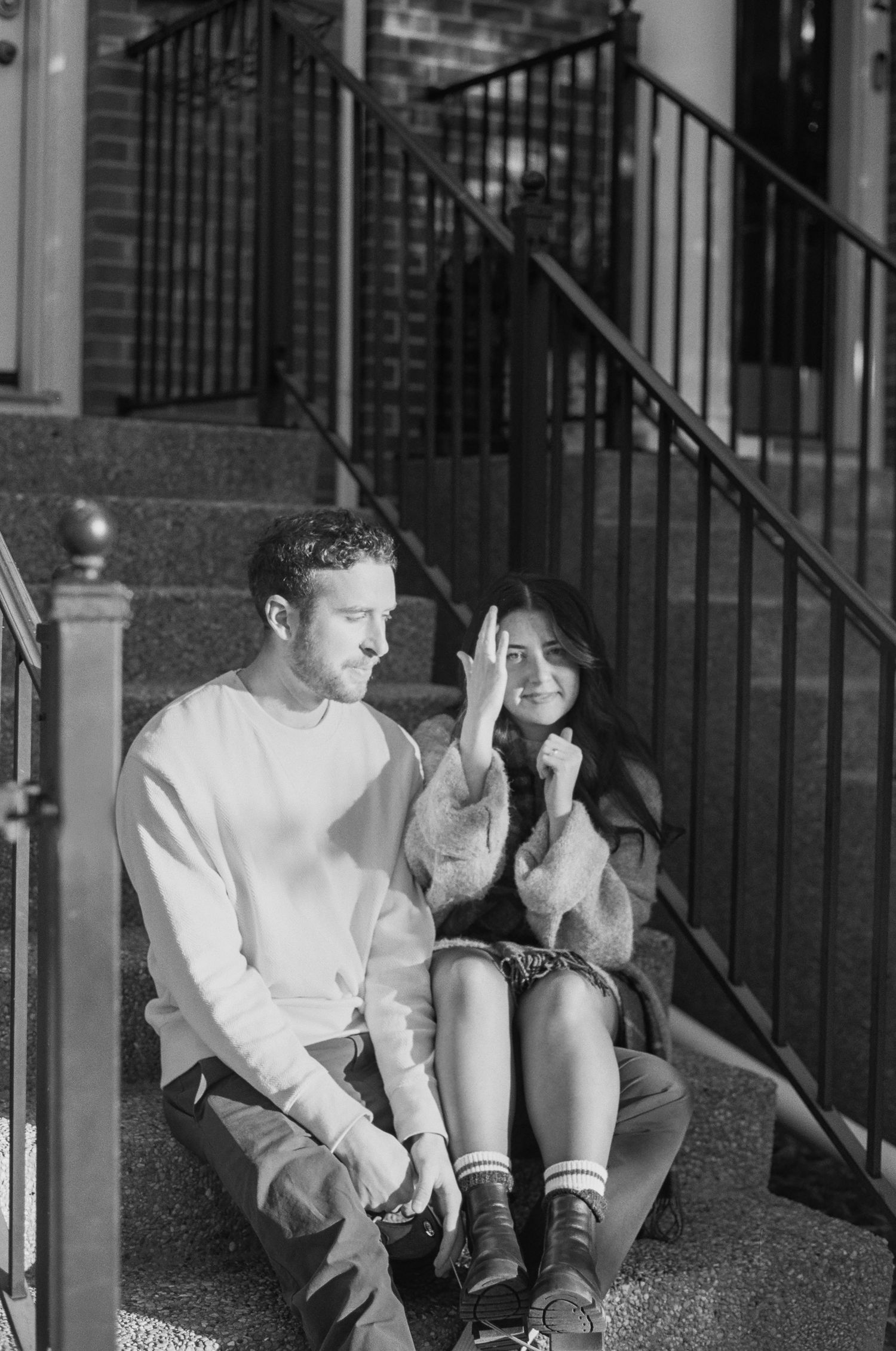 Black and white photo of a person sitting on outdoor steps wearing a light colored shirt.