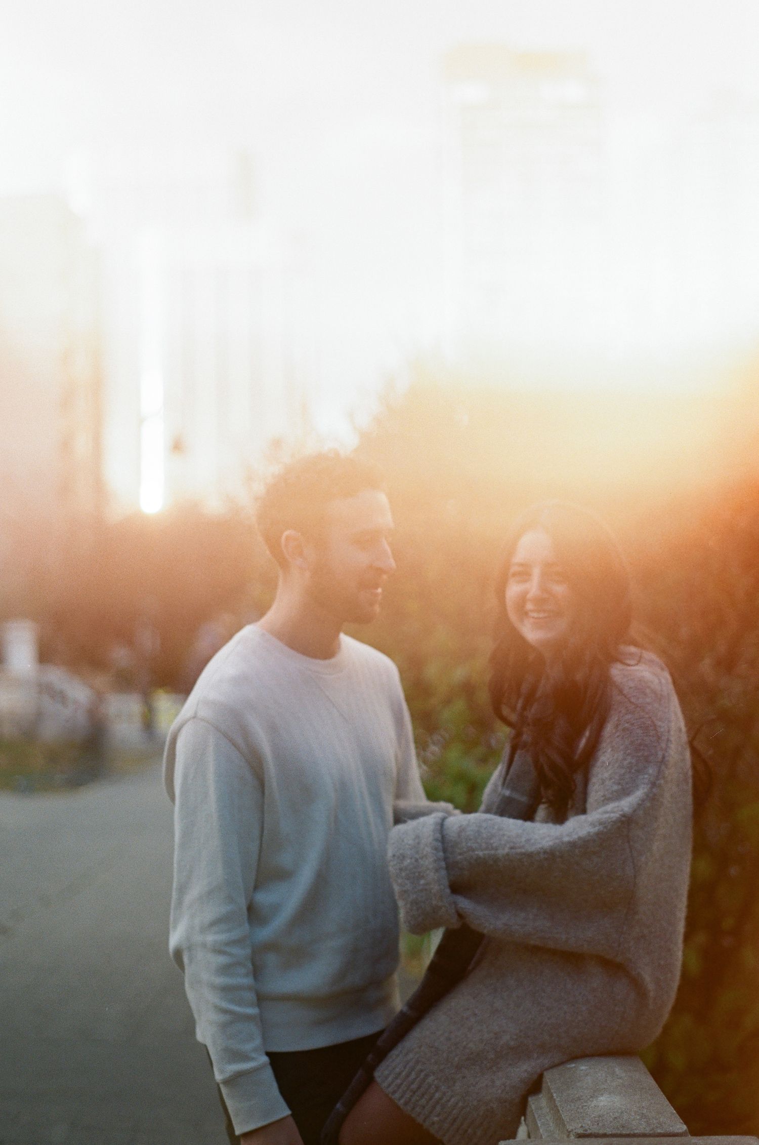 A couple shares a romantic moment together in a park during golden hour sunset.
