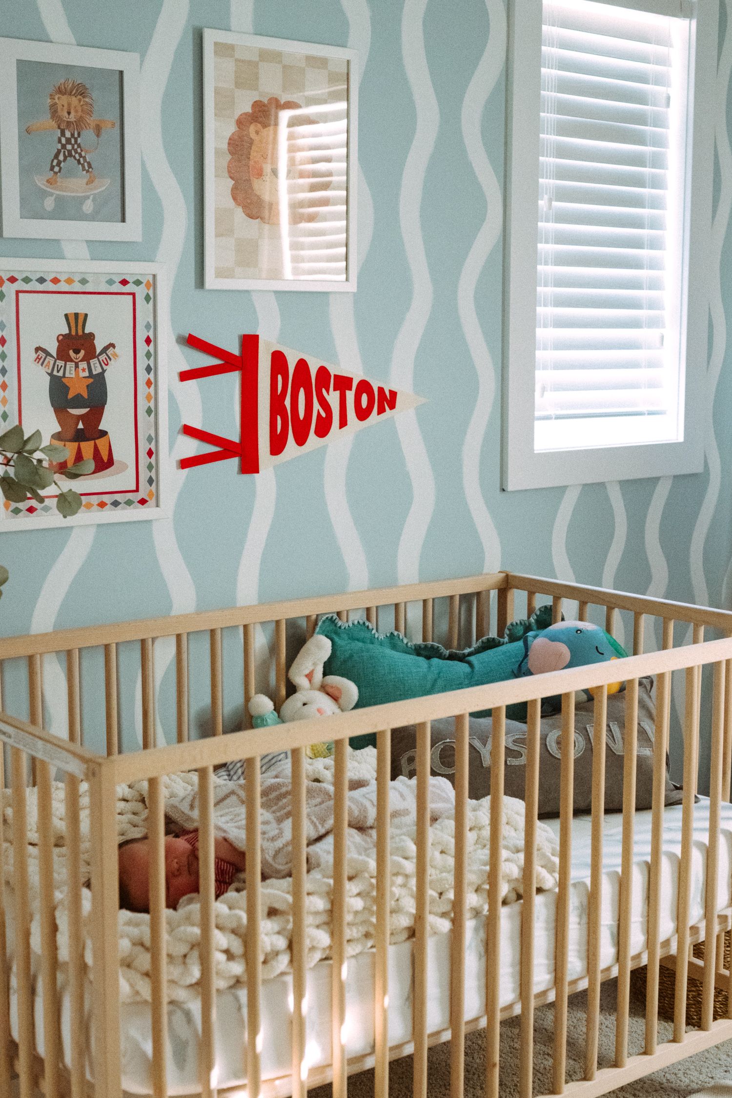 Baby nursery with light blue walls featuring teddy bear artwork and white wooden crib.