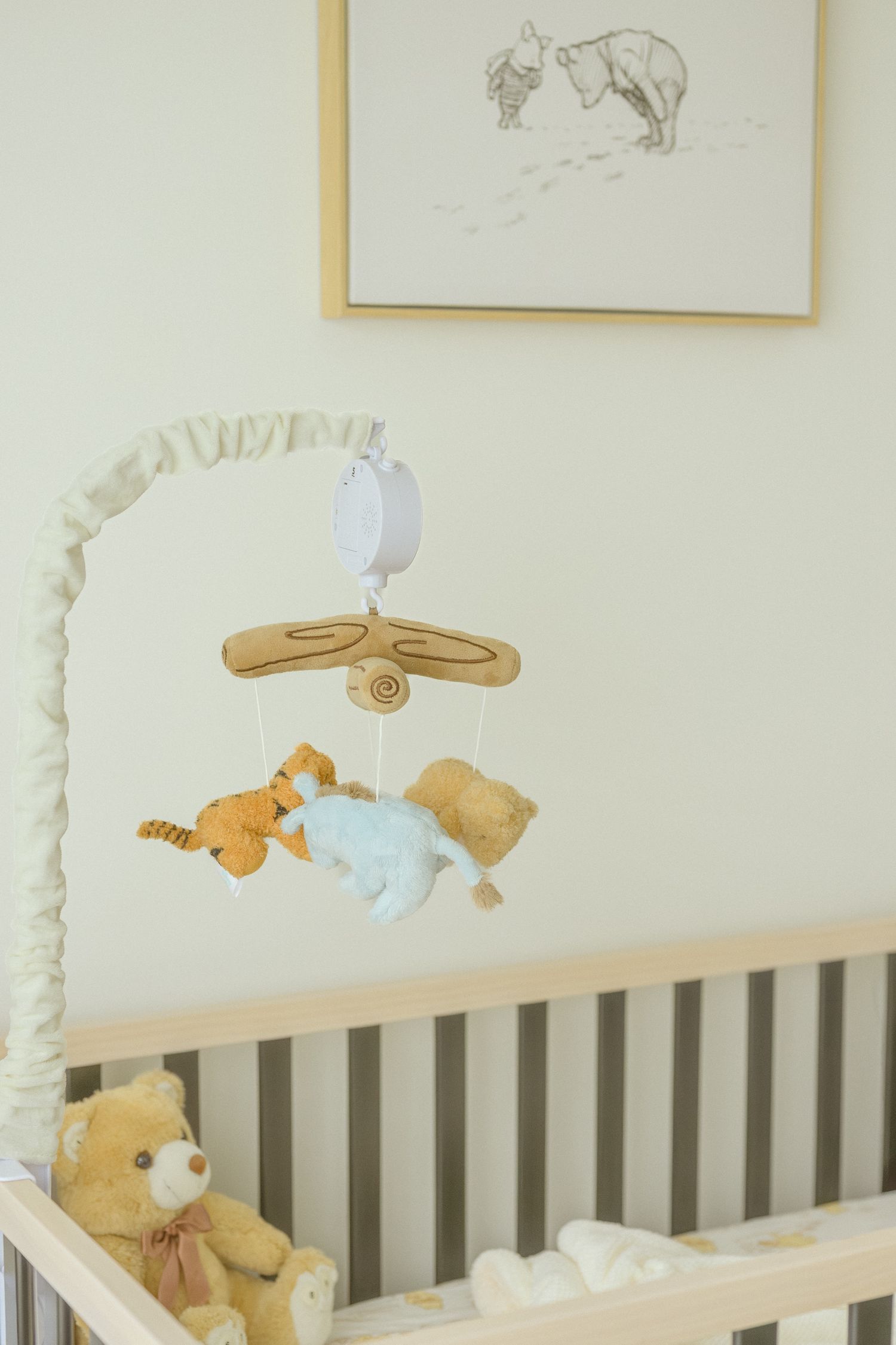 Baby mobile with plush animals hanging over gray crib.