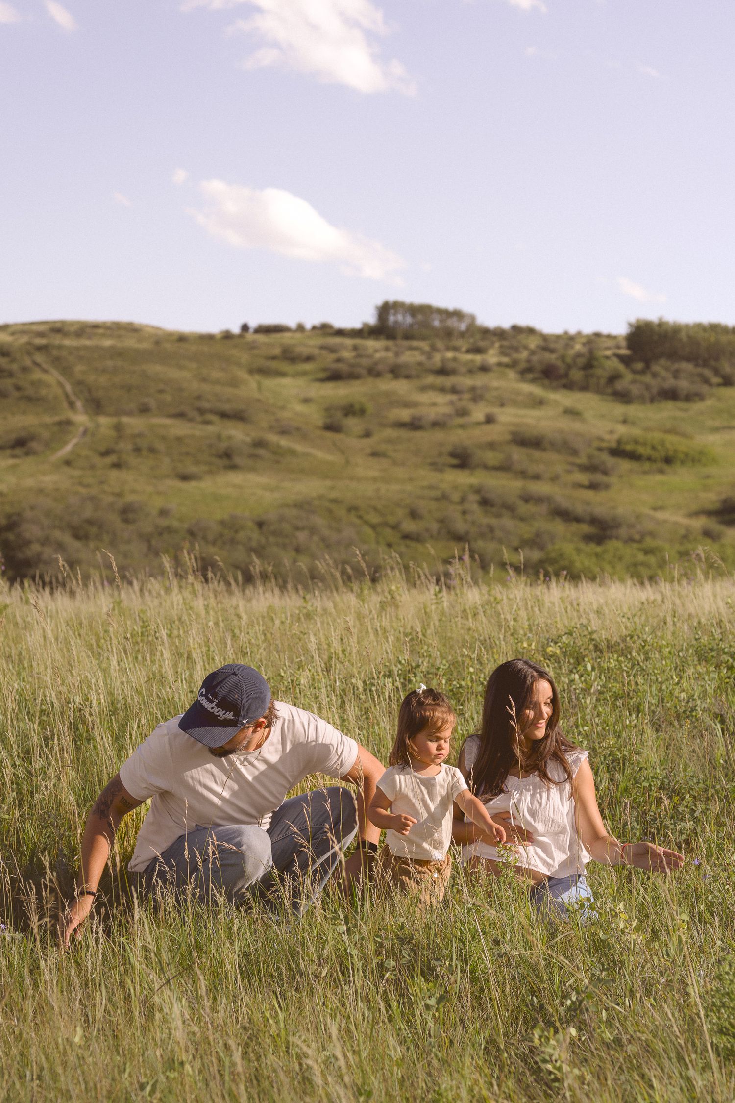 A group lying in tall grass on a hillside during golden hour.