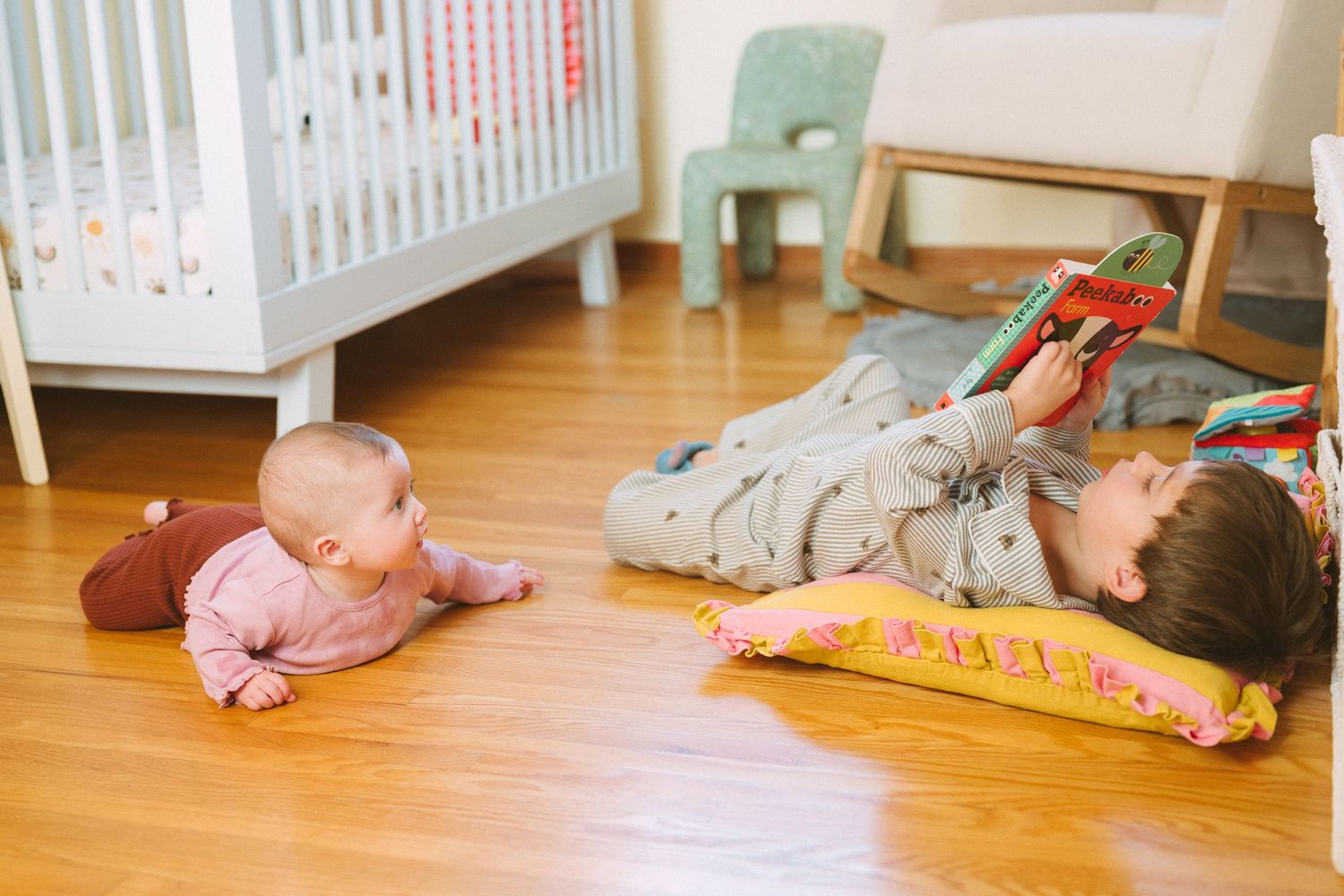 Panoramic view of nursery floor with scattered toys and white furniture.