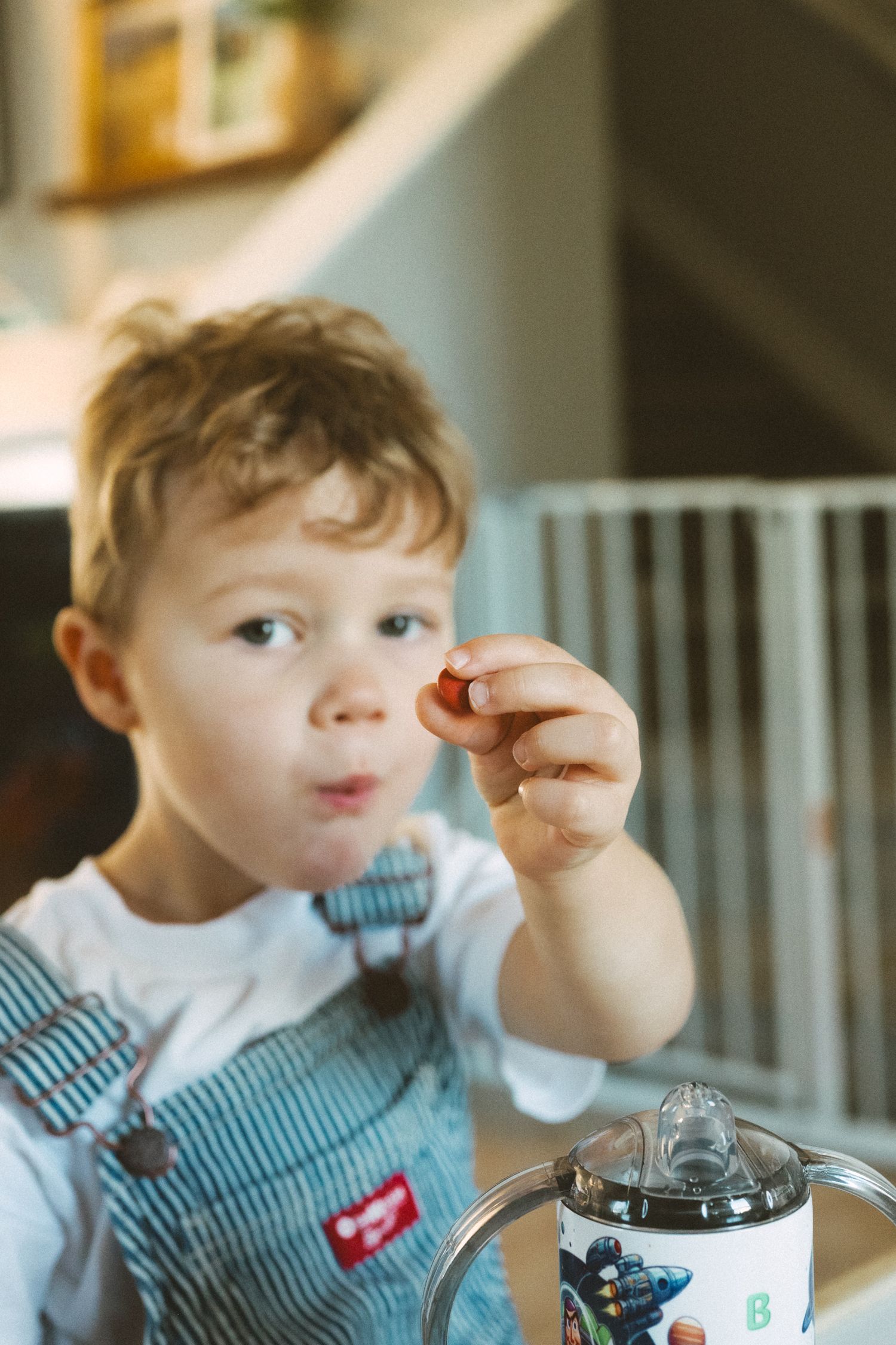 Child in a striped outfit enjoying a snack or drink while seated indoors.