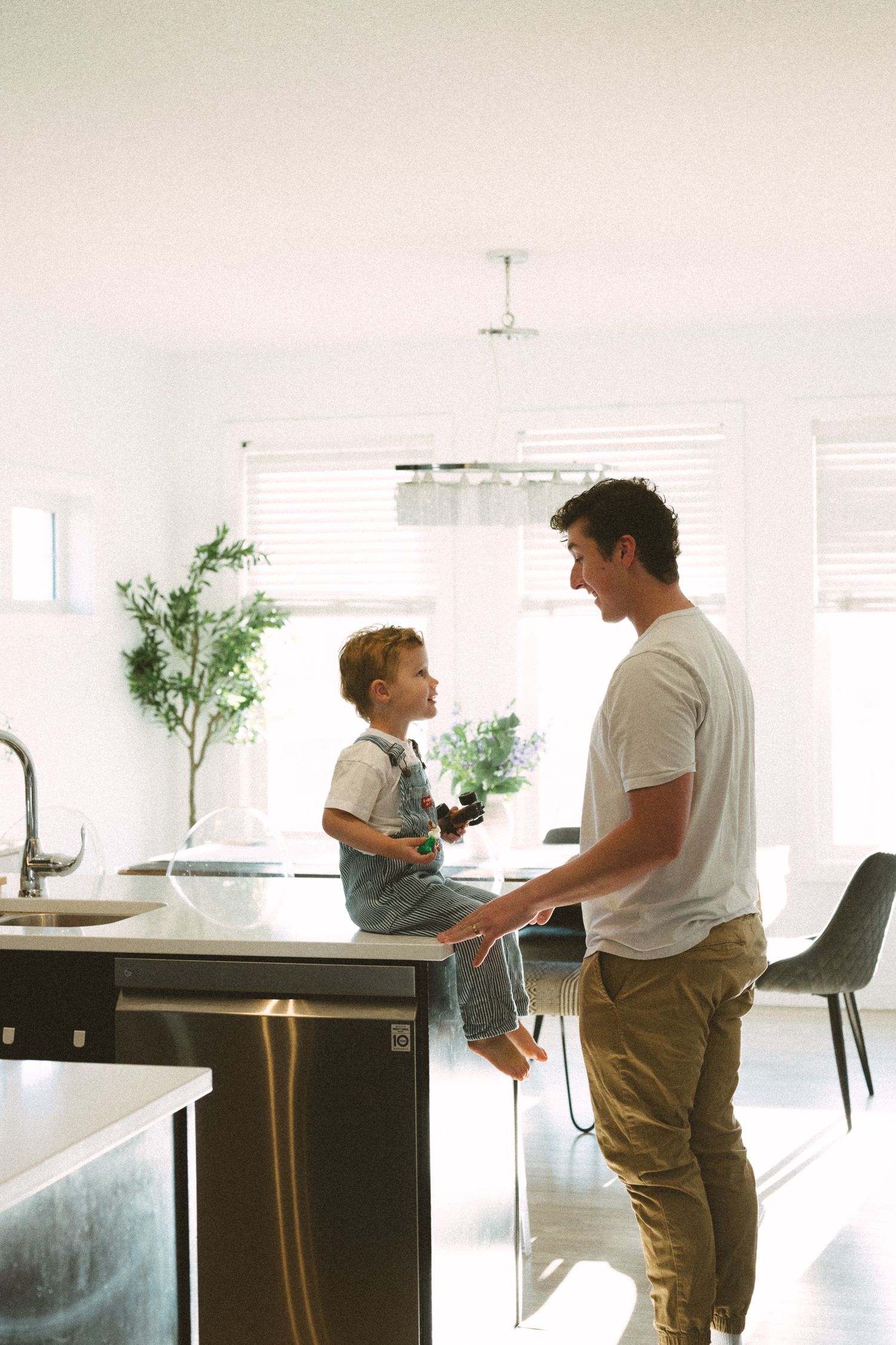 A series of four sequential photos showing two people interacting in a minimalist white interior space.