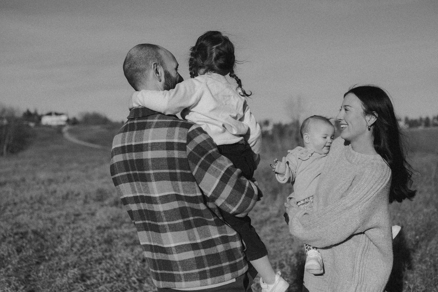 Black and white photo of a family enjoying time together outdoors in a rural field setting.