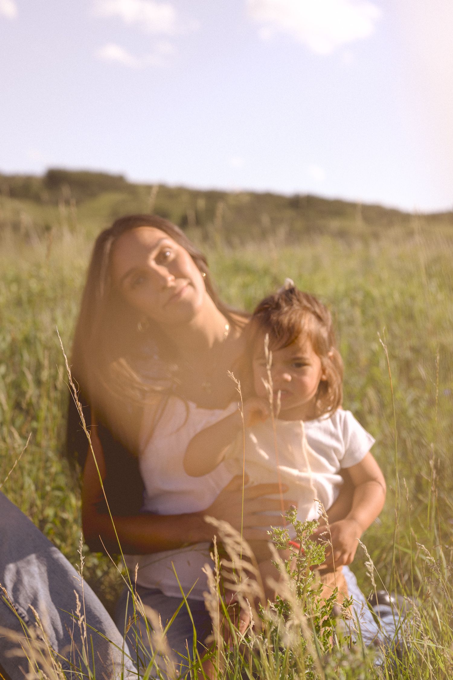 Two people share an intimate moment while relaxing in a sunny meadow.