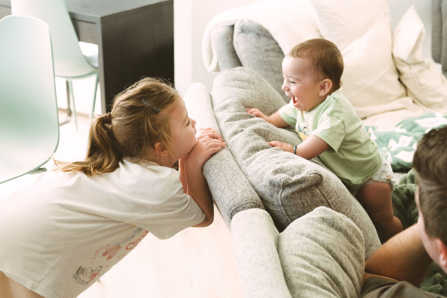 Playful interaction between family members on a comfortable couch with soft blankets.