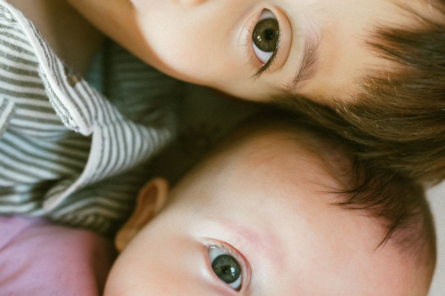 Candid portrait of children relaxing on a patterned sheet.