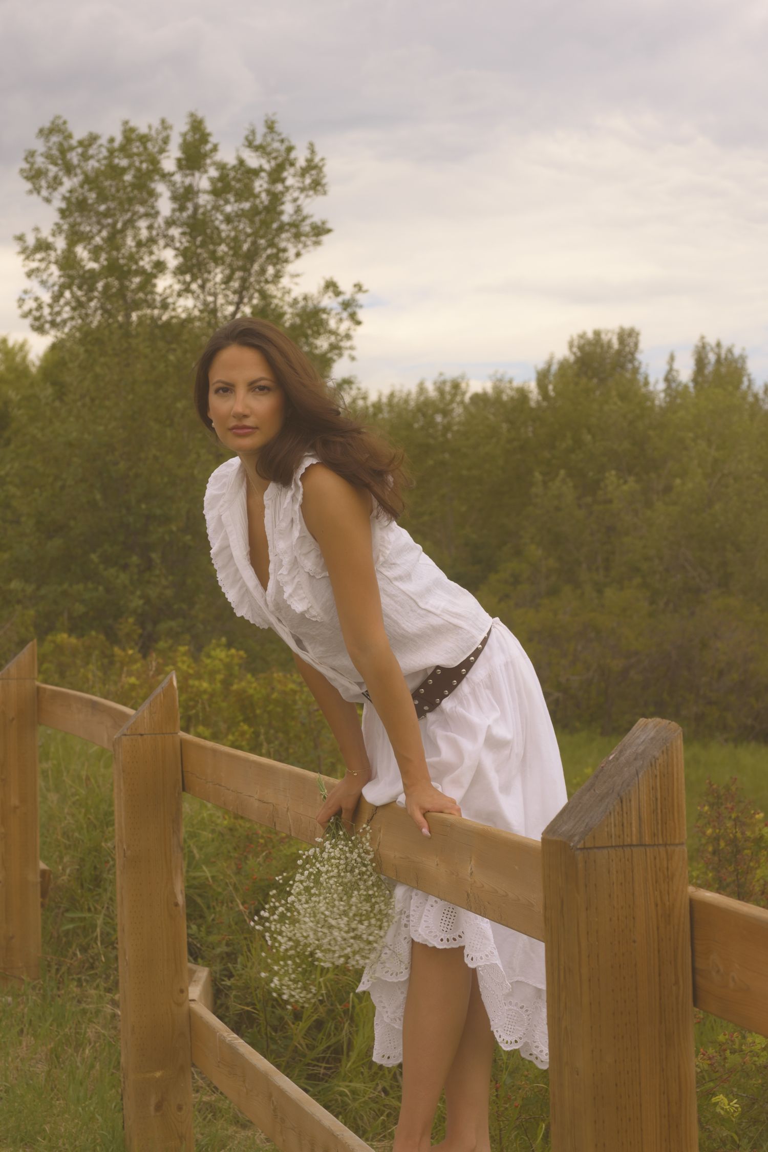 Summer portrait on a wooden fence surrounded by lush greenery and trees.