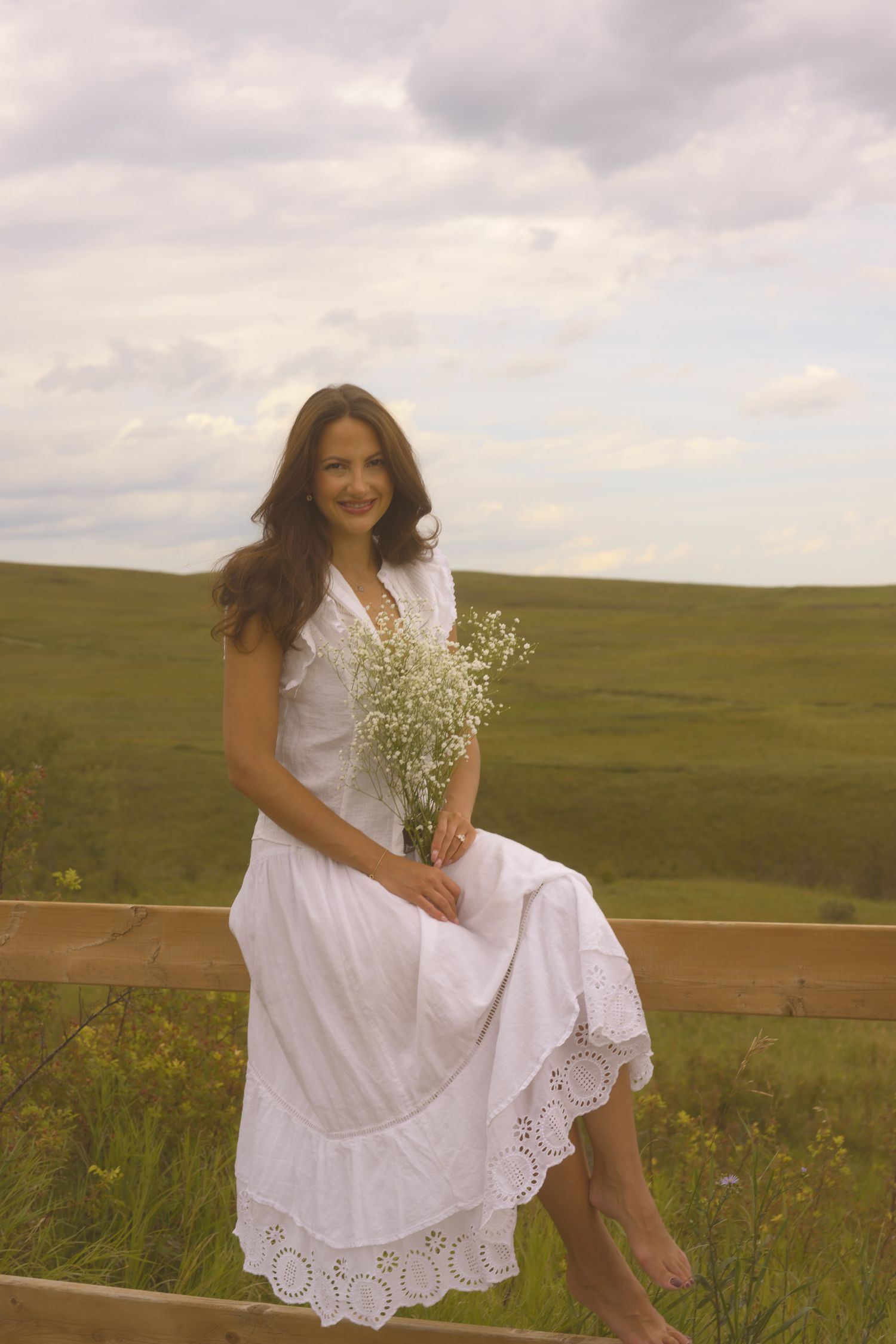 Ethereal countryside photoshoot featuring a white cotton dress and wildflower bouquet.