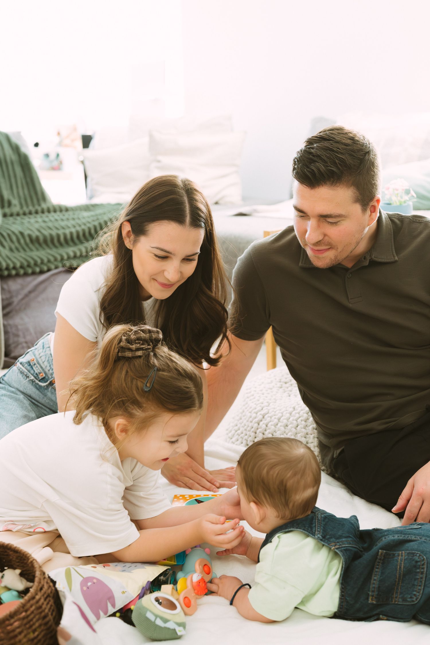 Family enjoying quality time together on a cozy bed while playing with colorful toys.
