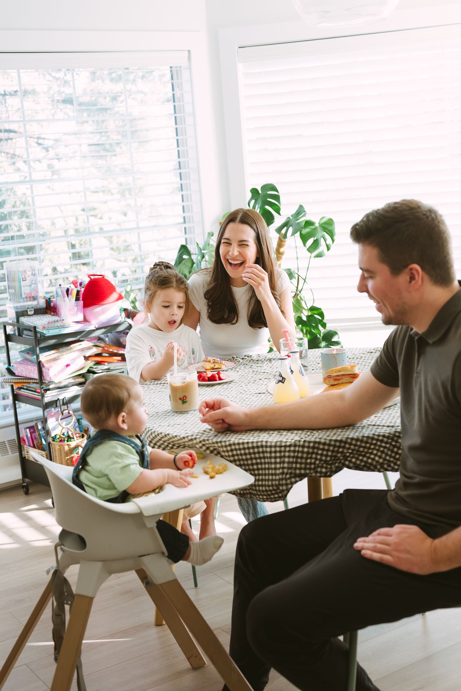 Family gathering around dining table with checkered tablecloth for a casual meal together.