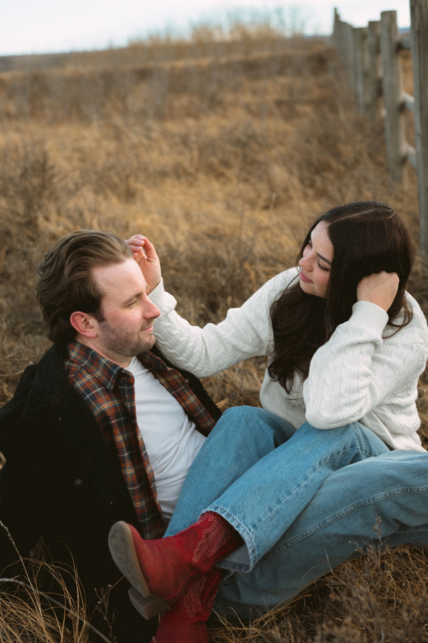 A couple in casual clothing lying together on brown grass during autumn.