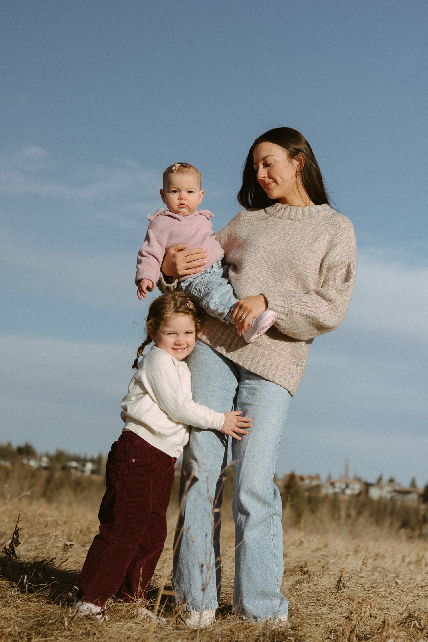 A heartwarming family scene unfolds against a blue sky backdrop in an outdoor setting.