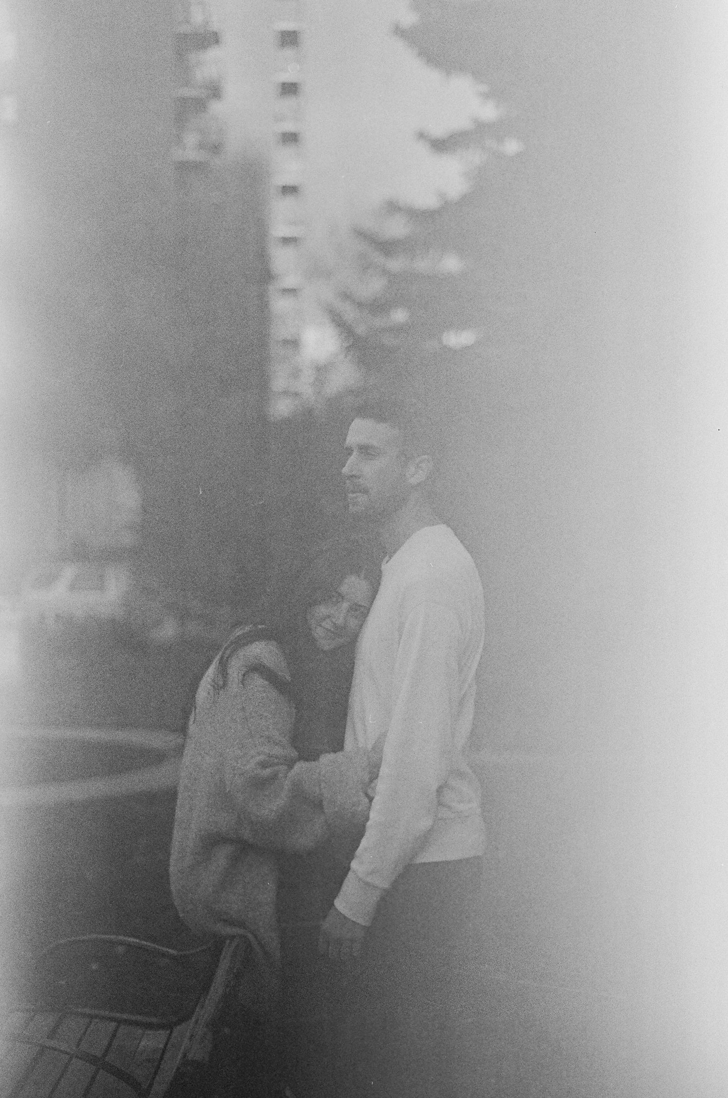 A dreamy black and white photograph showing a person in a white sweater standing outdoors near birch trees in soft focus.