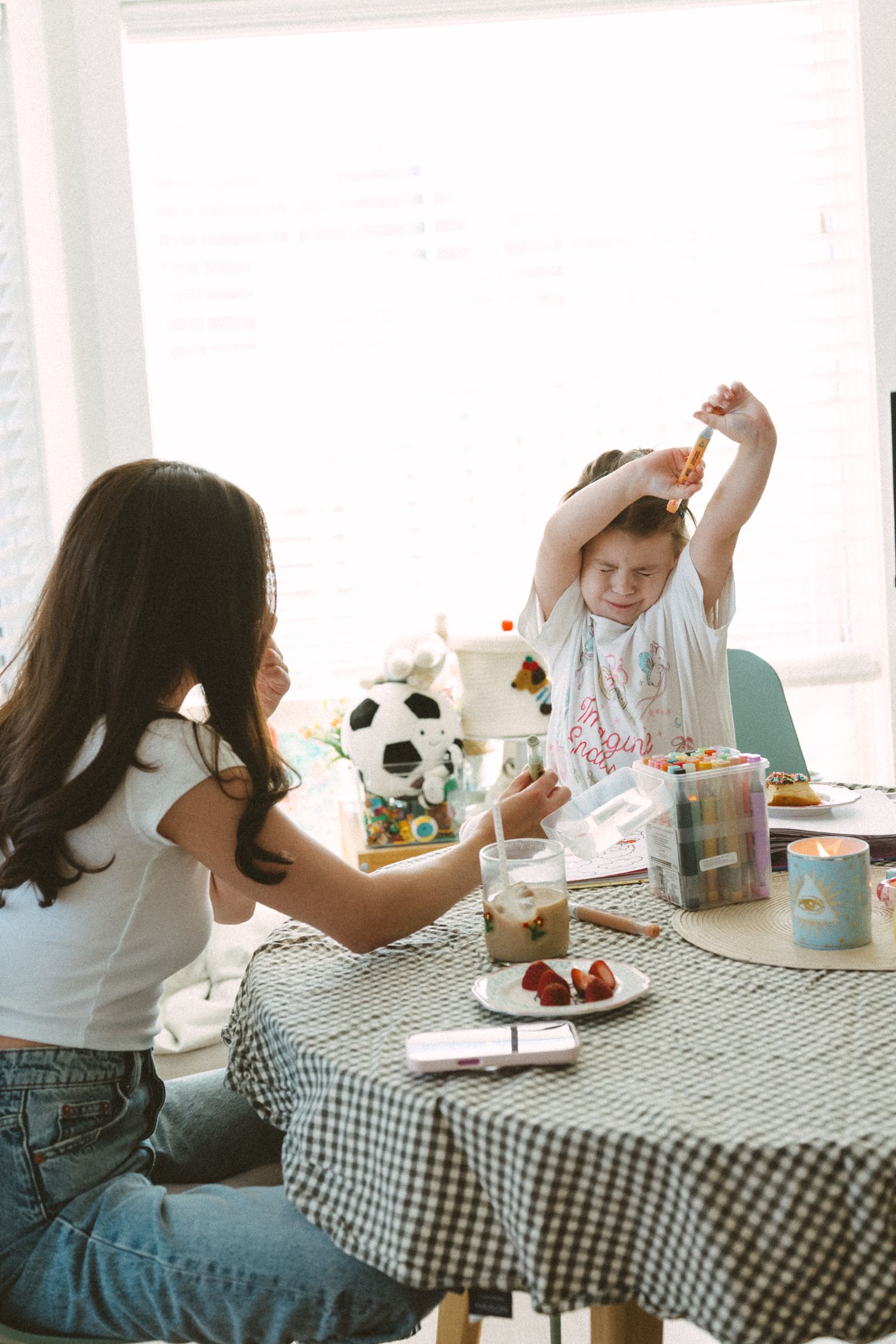 People gather around a checkered tablecloth to celebrate and enjoy cake together at a party.