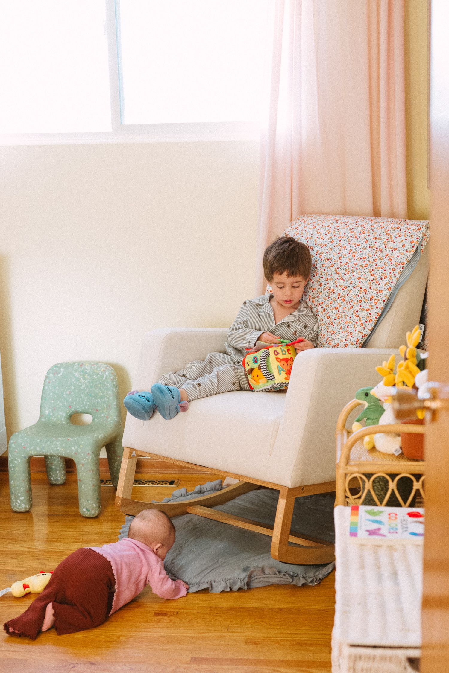 Modern nursery with white furniture and wooden floors in natural light.