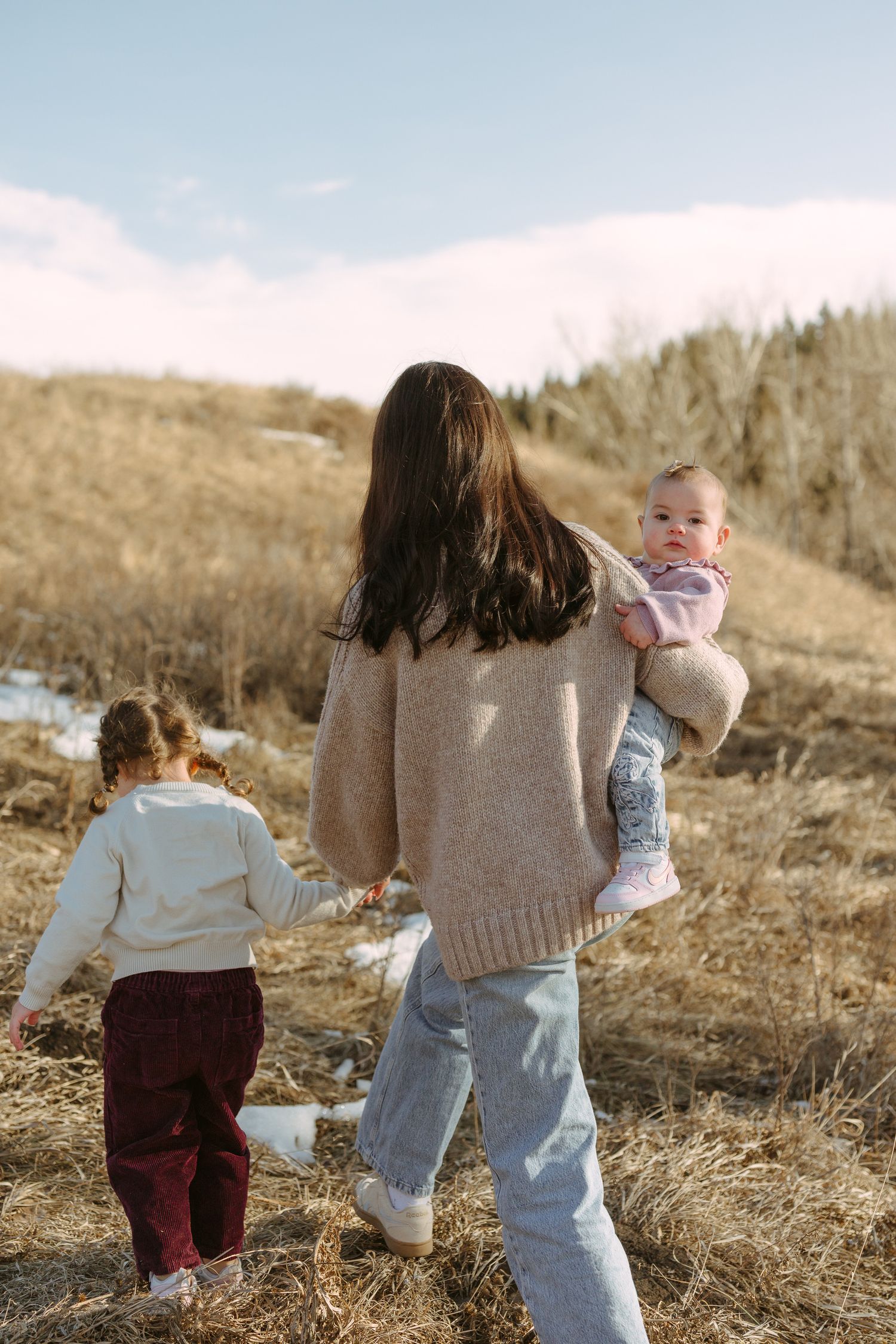 A family walking together through a golden field on a bright autumn day.