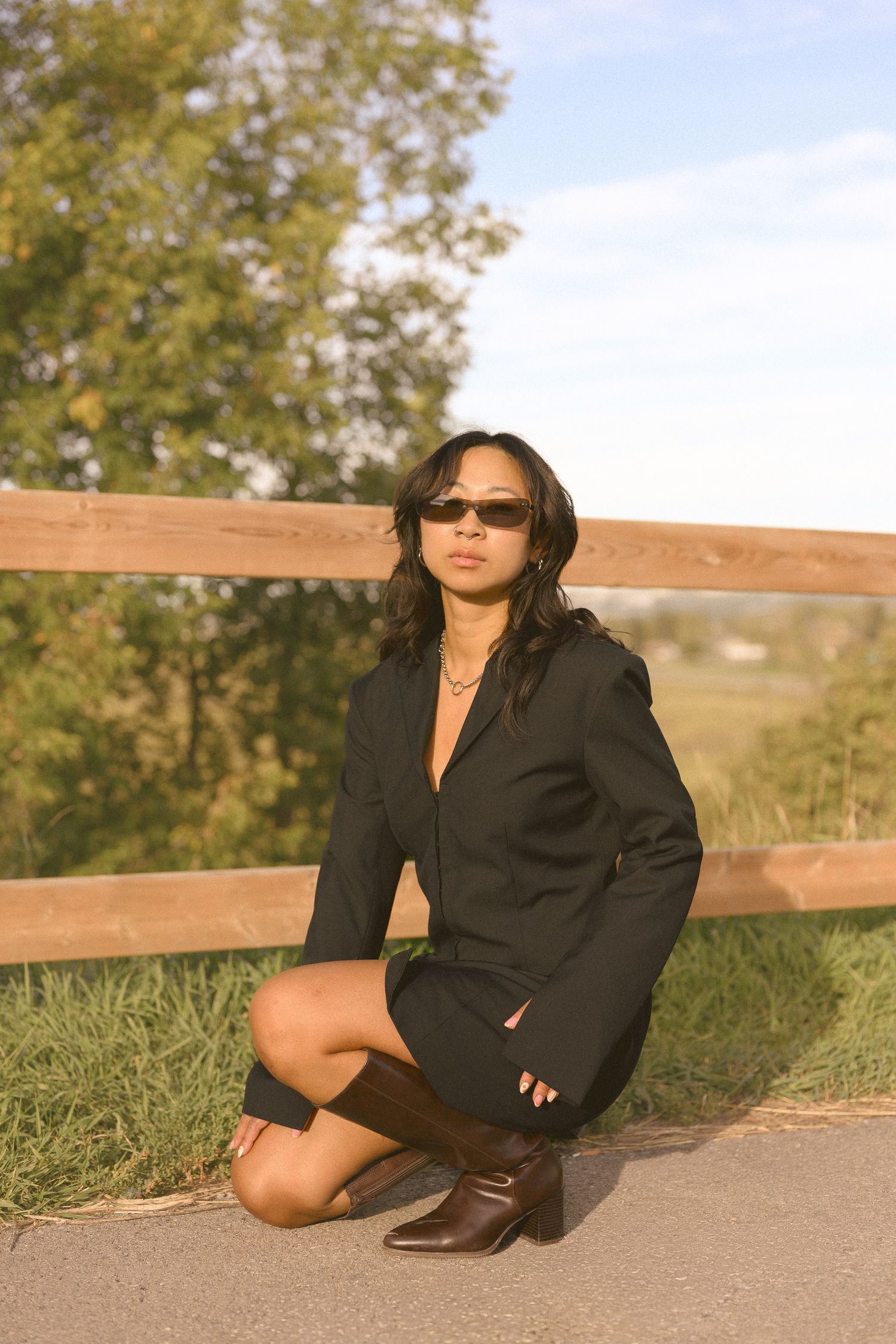 A fashionable black blazer outfit photographed against a wooden fence at sunset.