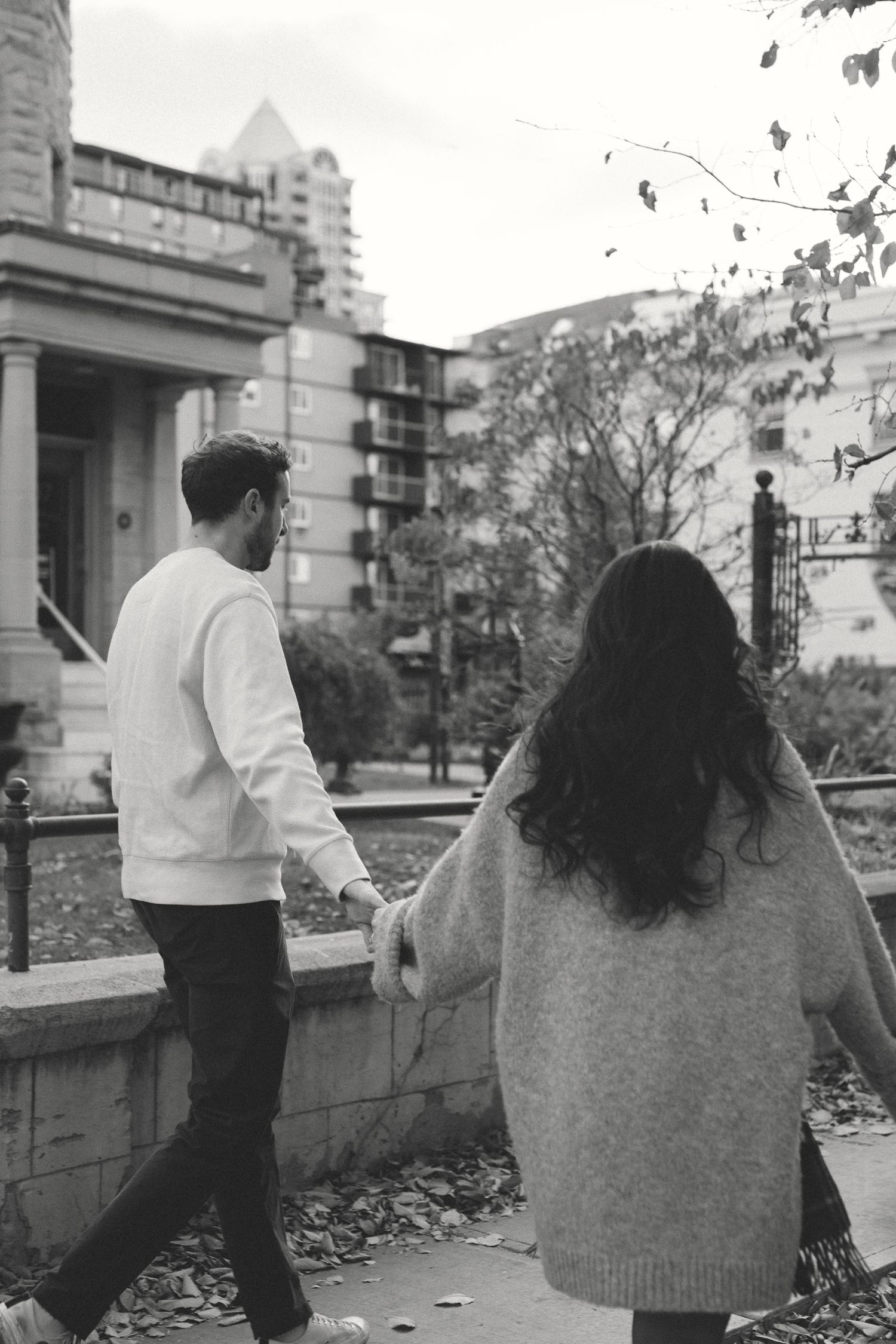 Black and white sequence showing two people walking together outdoors in an urban setting.