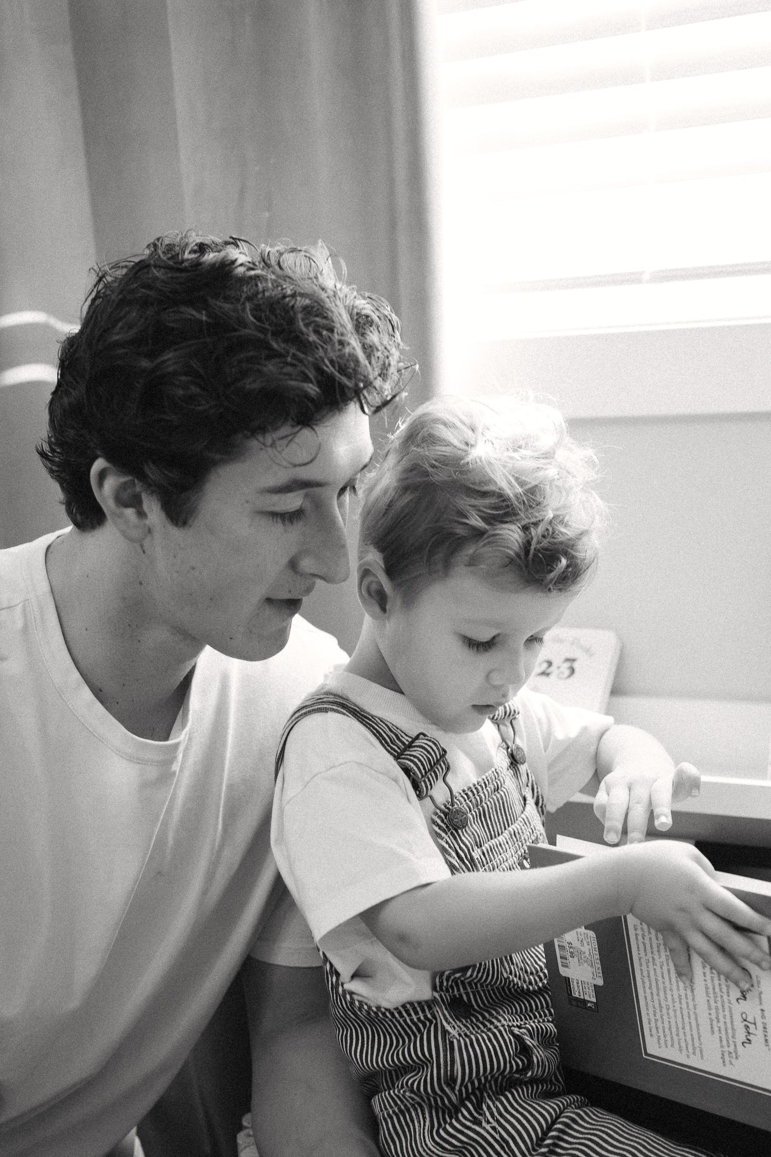Black and white photo series showing a parent and child reading together at a table.