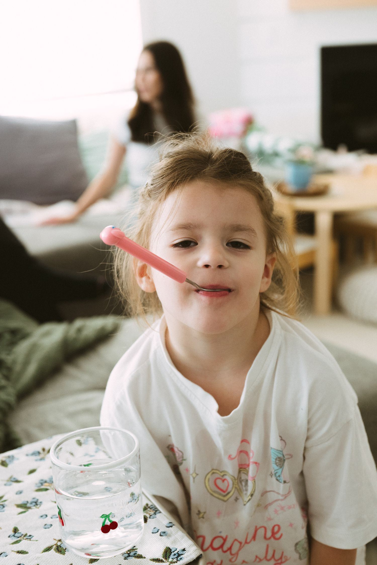 A candid moment at home showing someone drinking from a pink straw with a floral tablecloth visible.