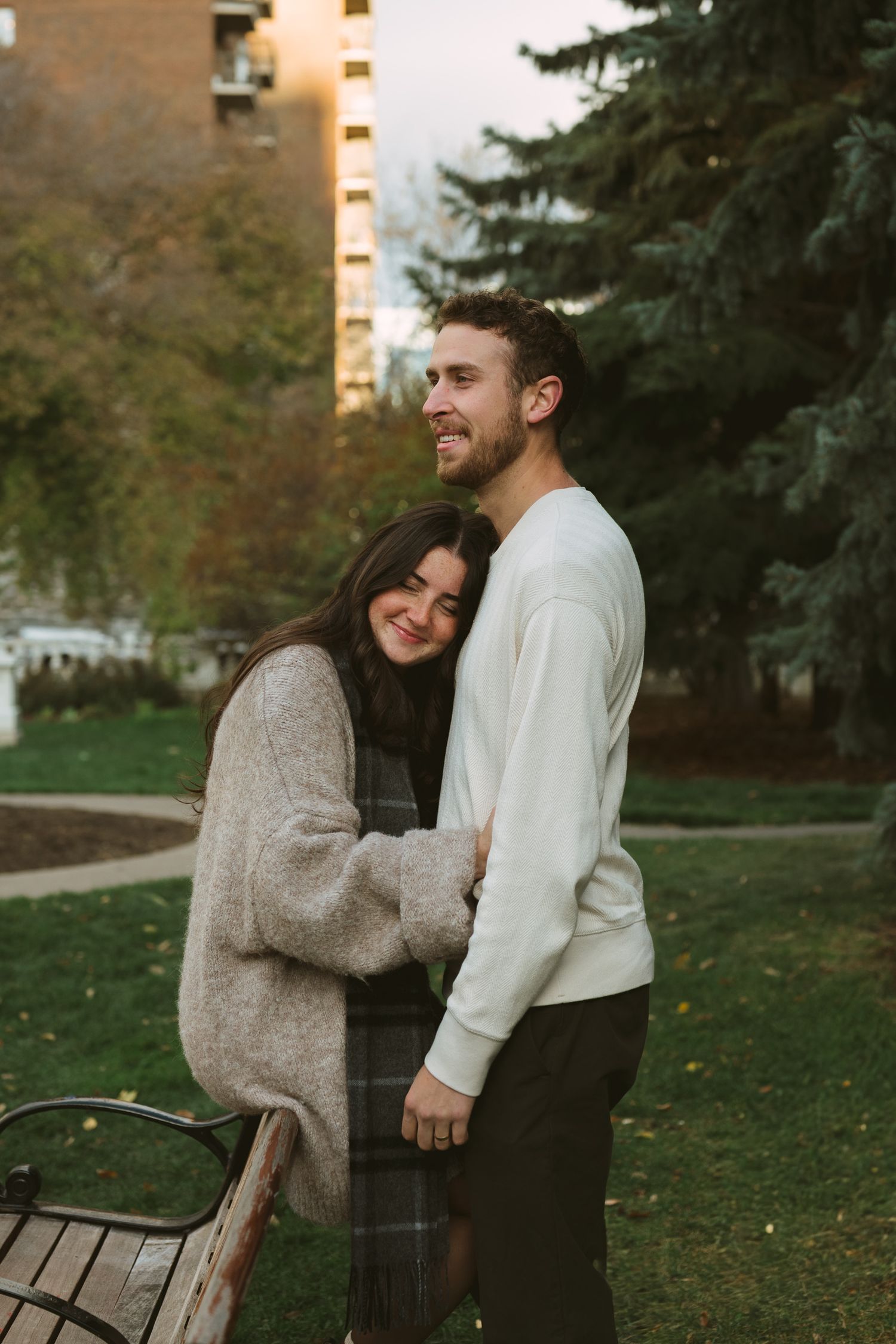 A couple shares a tender moment together while standing in a park during autumn at sunset.