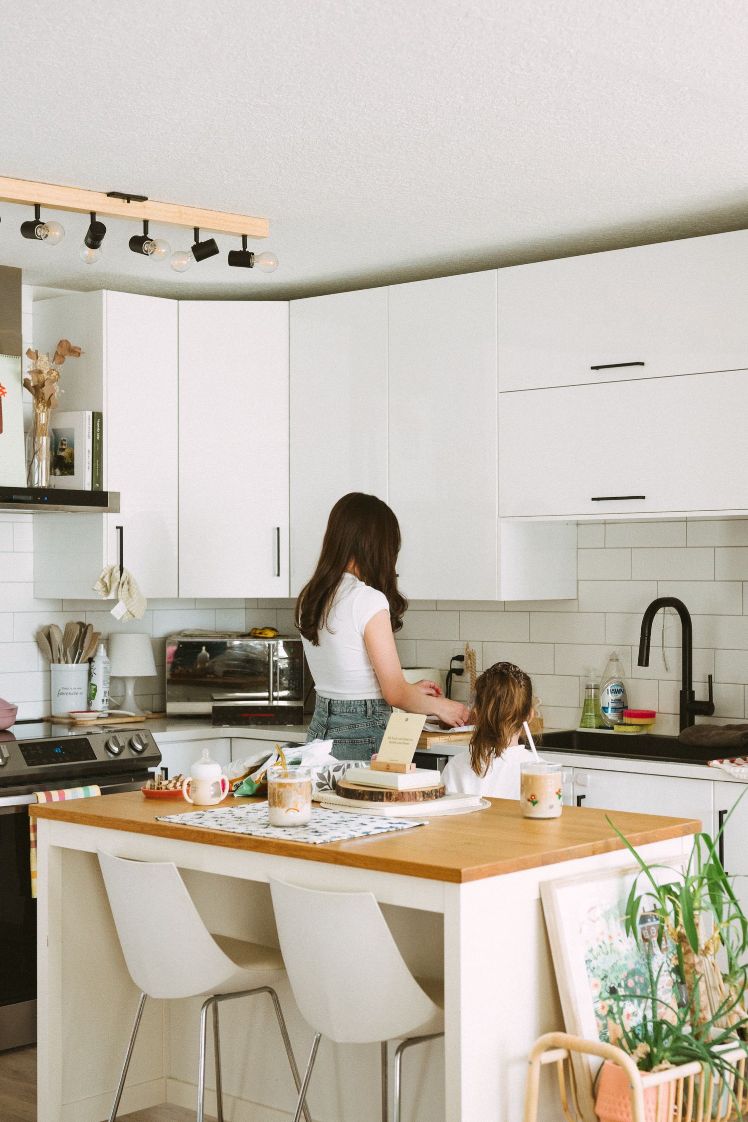 Modern white kitchen with butcher block island, subway tile backsplash, and minimalist bar stools.