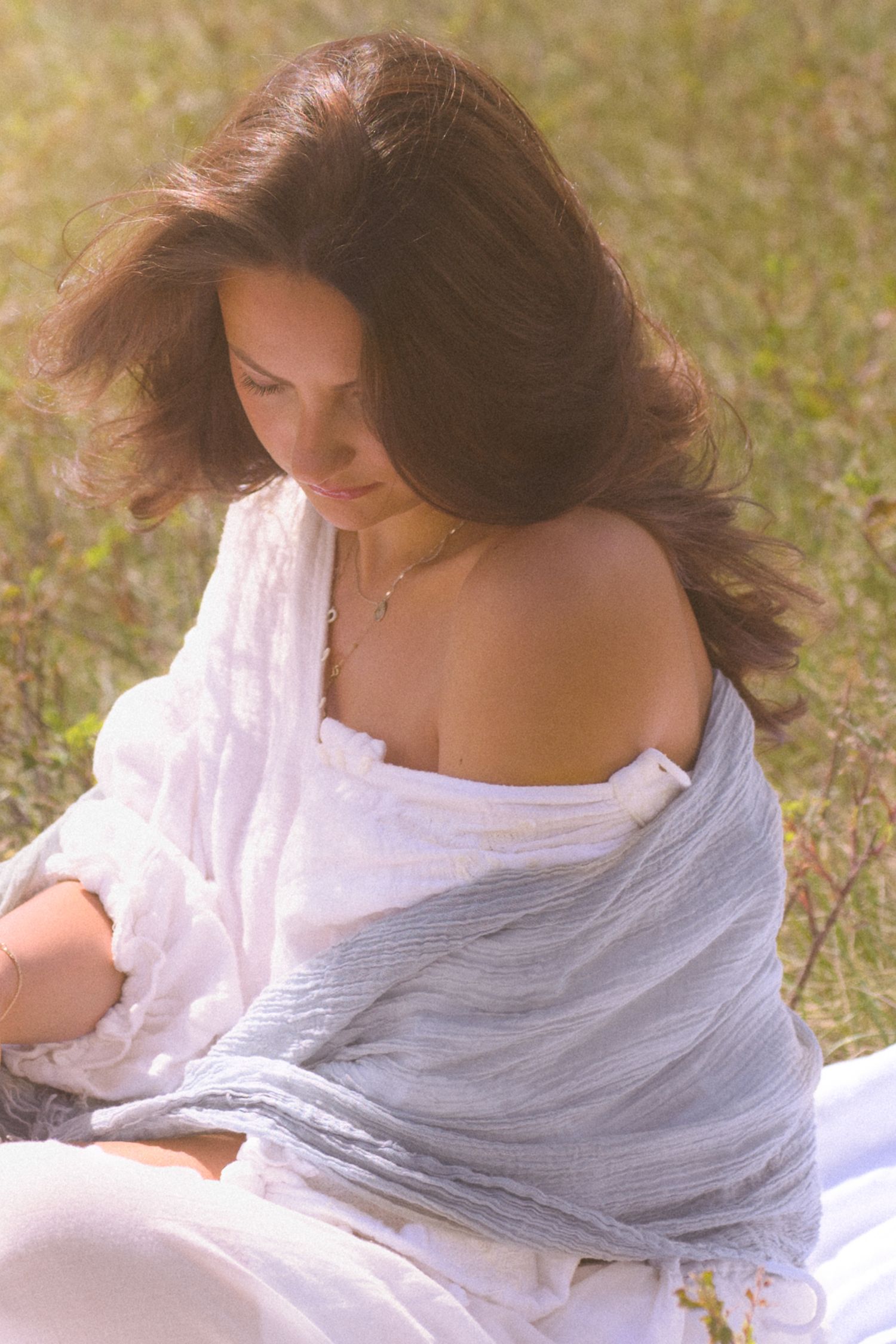 Soft, ethereal portrait with white fabric and natural lighting in a meadow setting.