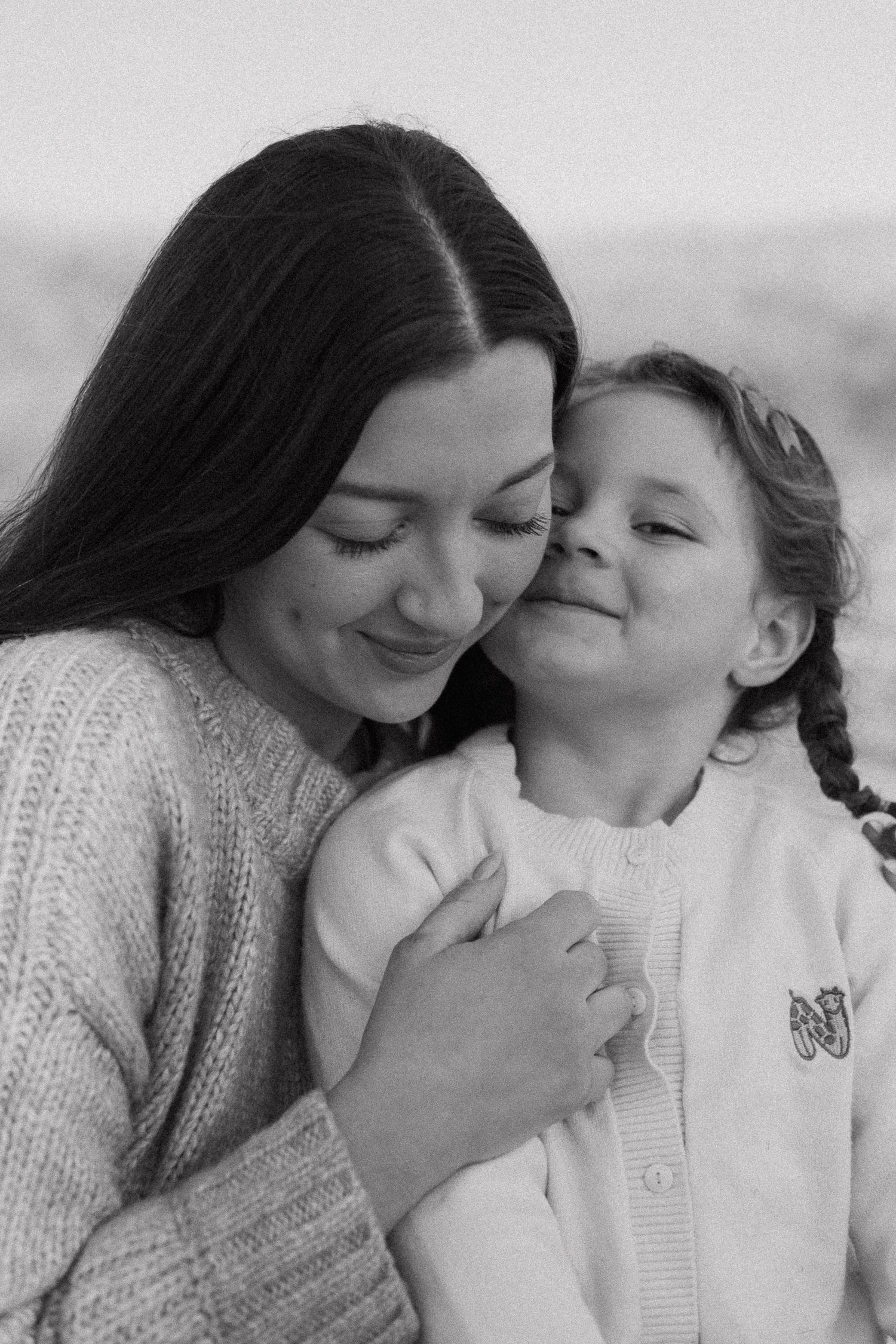 A series of intimate black and white photos showing tender moments between parent and child in matching sweaters.