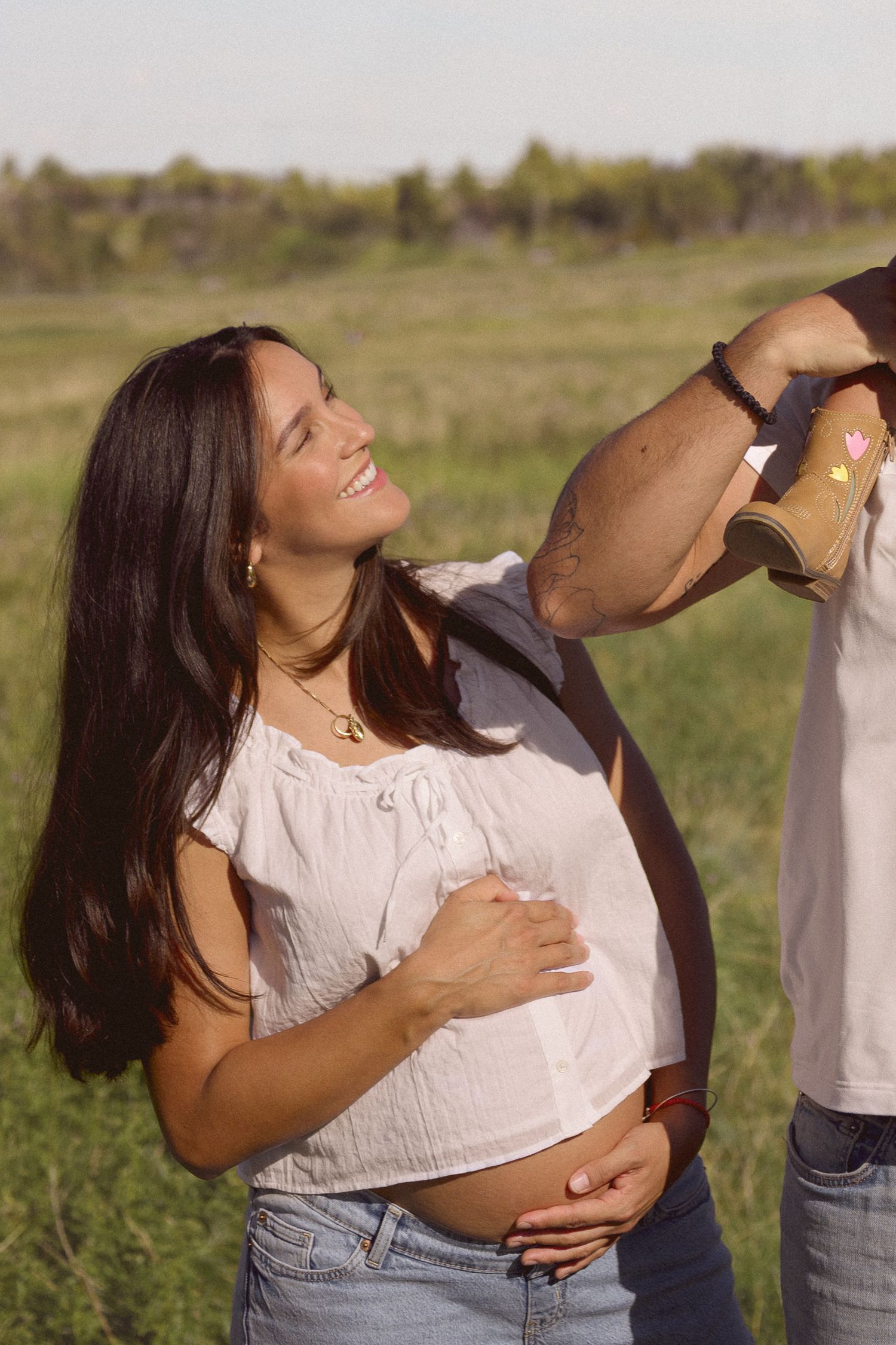 Woman in white blouse and jeans enjoys a carefree moment in a grassy field.