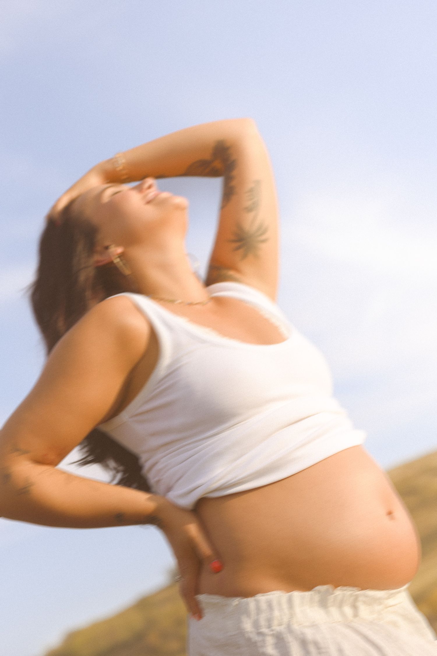 Dreamy backlit maternity poses captured against bright sky showing pregnancy silhouette.