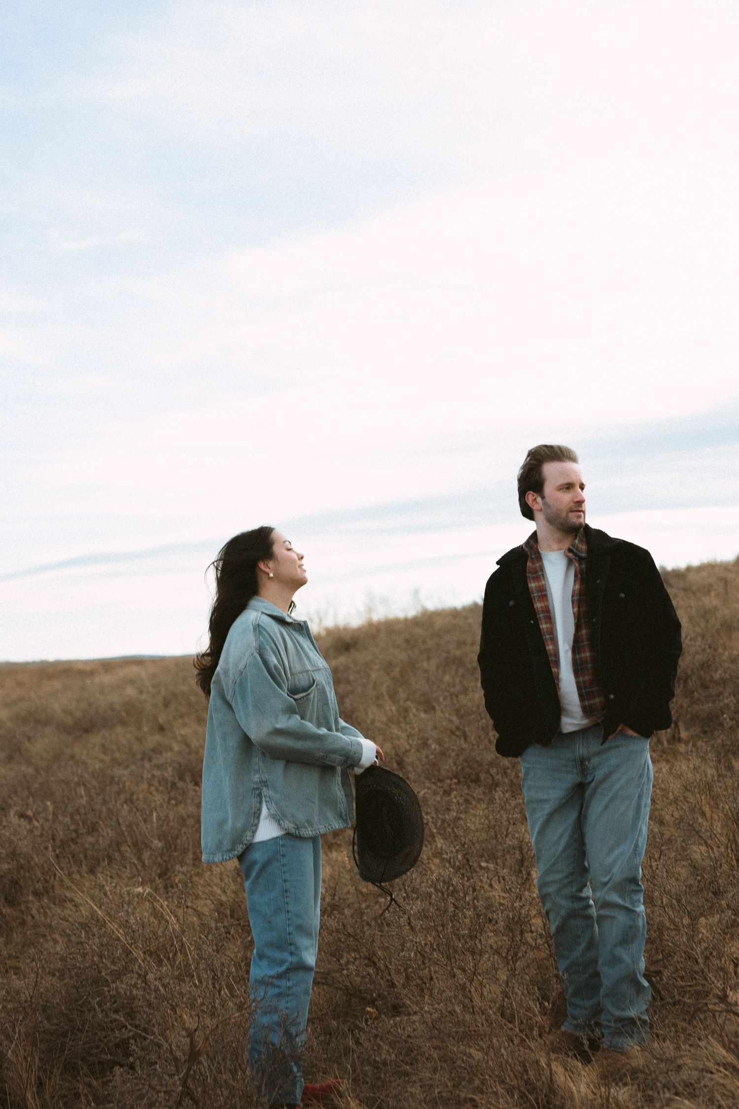 Casual couple in denim interacting playfully in a golden prairie field.
