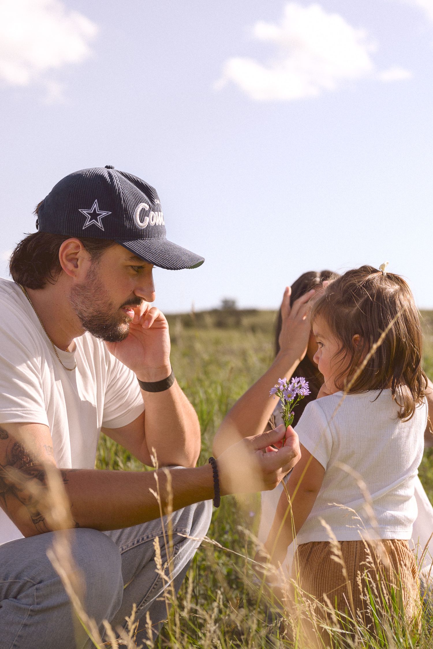 Family enjoying a tender moment together in a sunlit field of wildflowers.