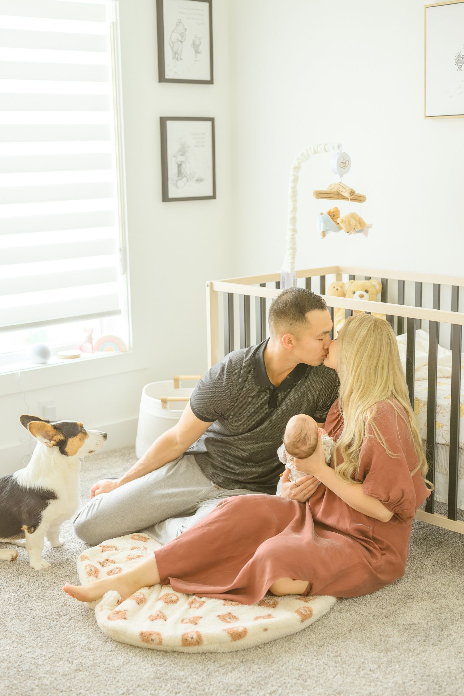 Family relaxes on floor cushions in nursery with their dog and baby.
