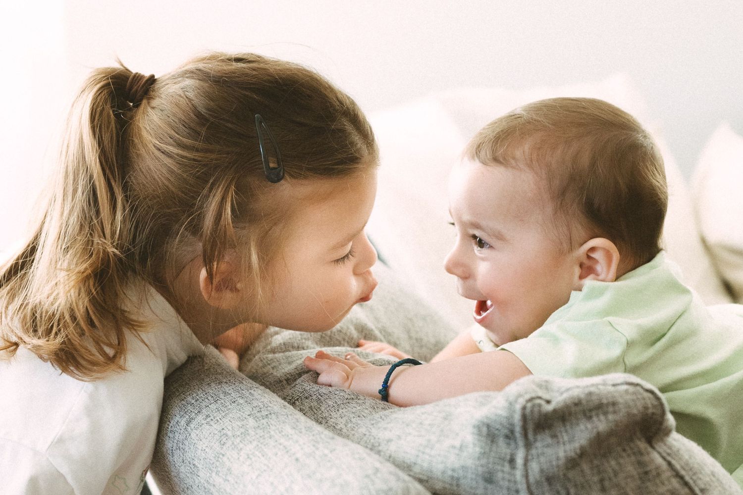 Two children sharing a sweet bonding moment together while sitting on a couch.