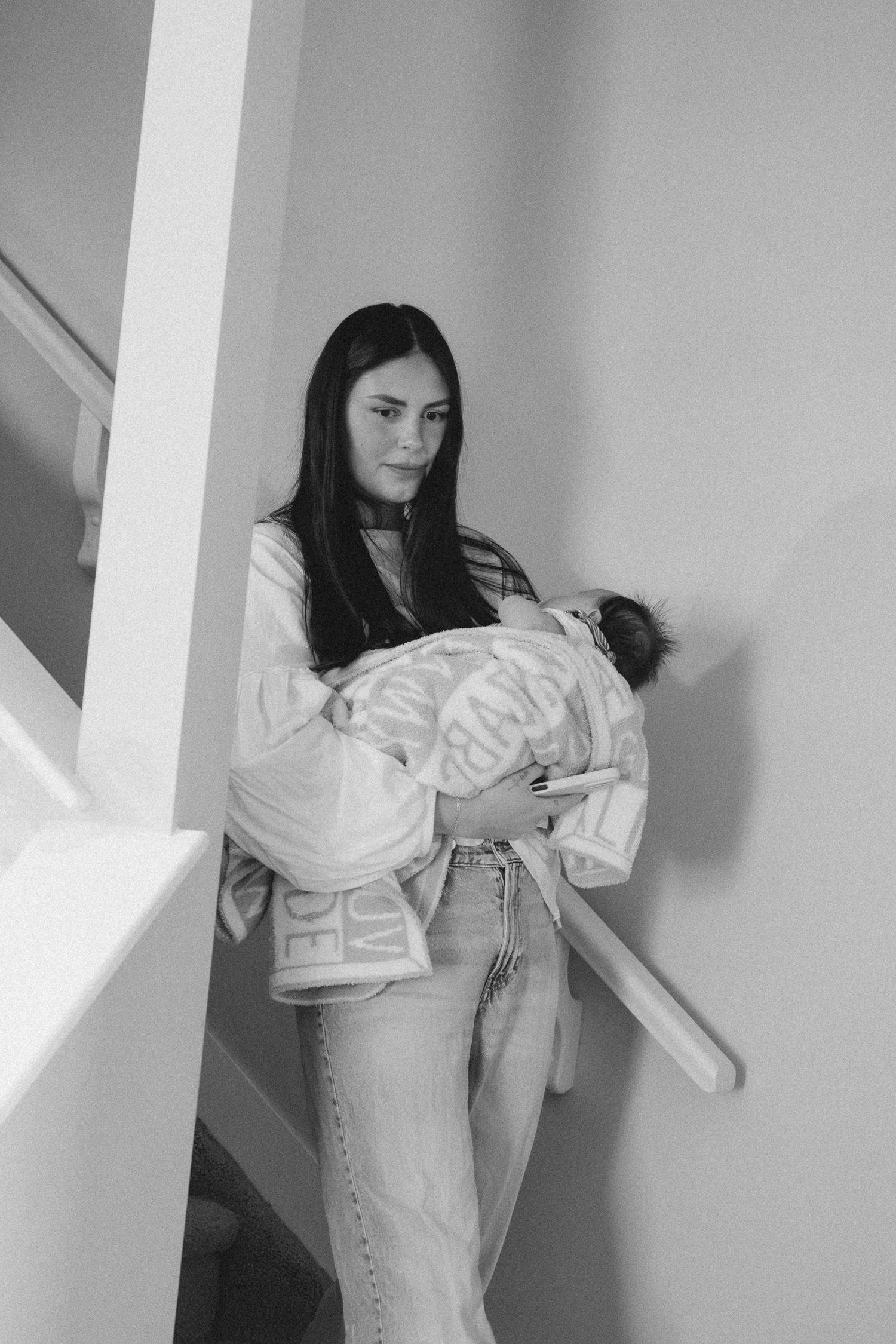 Black and white photo series showing intimate moments between a parent and baby in a minimalist interior setting.