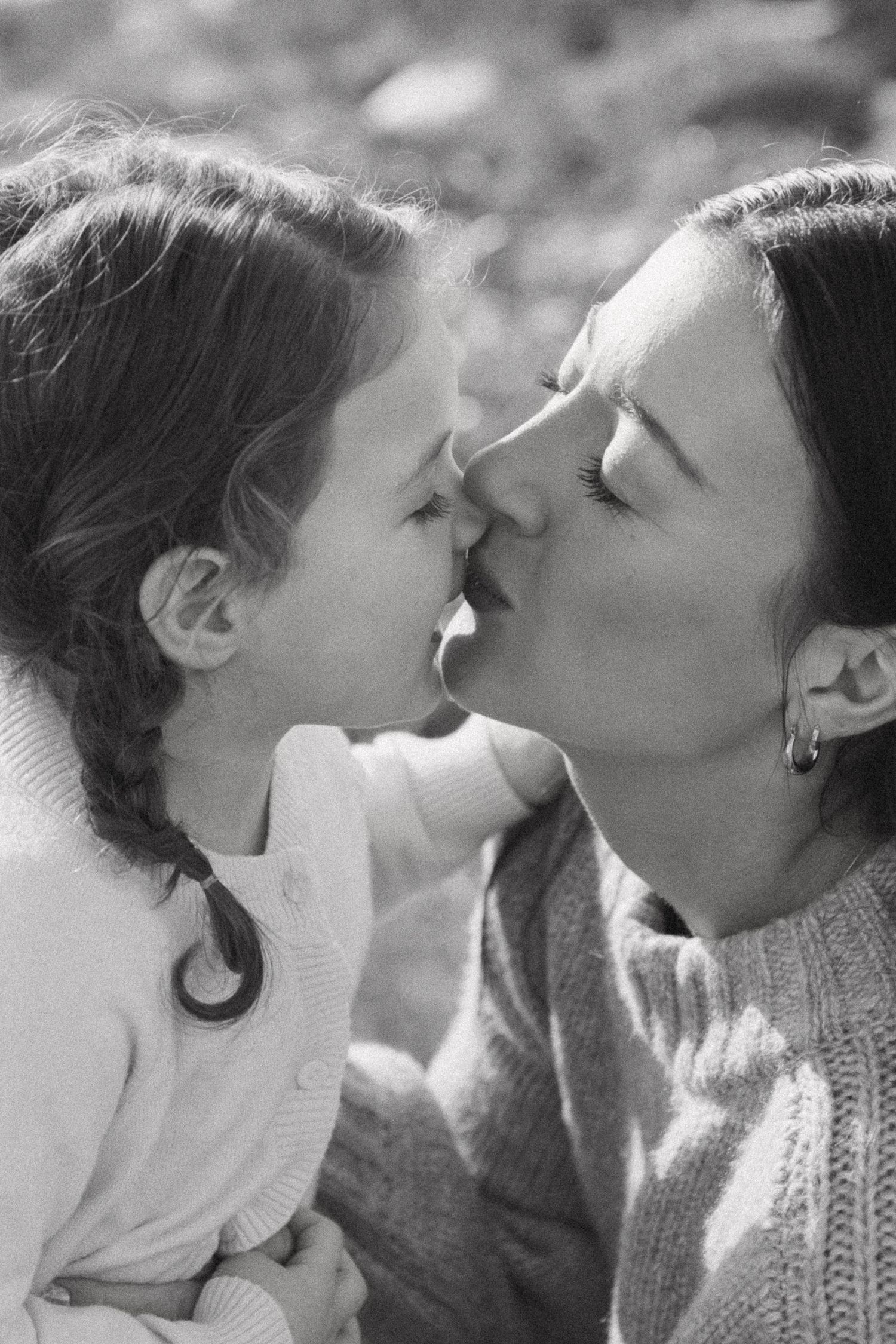 A tender black and white photograph capturing an intimate moment of affection between parent and child.