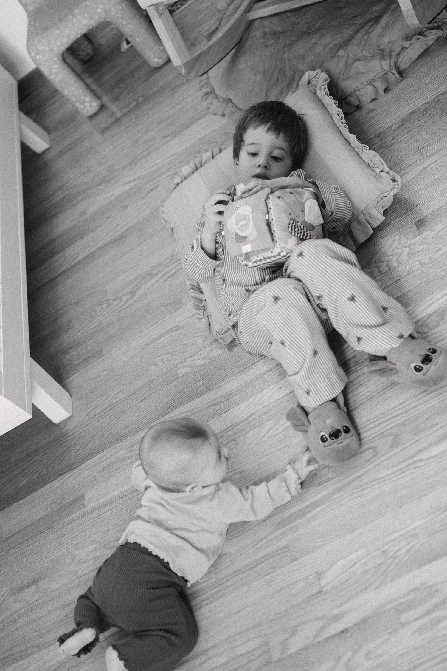 Black and white image of children playing on hardwood floor.