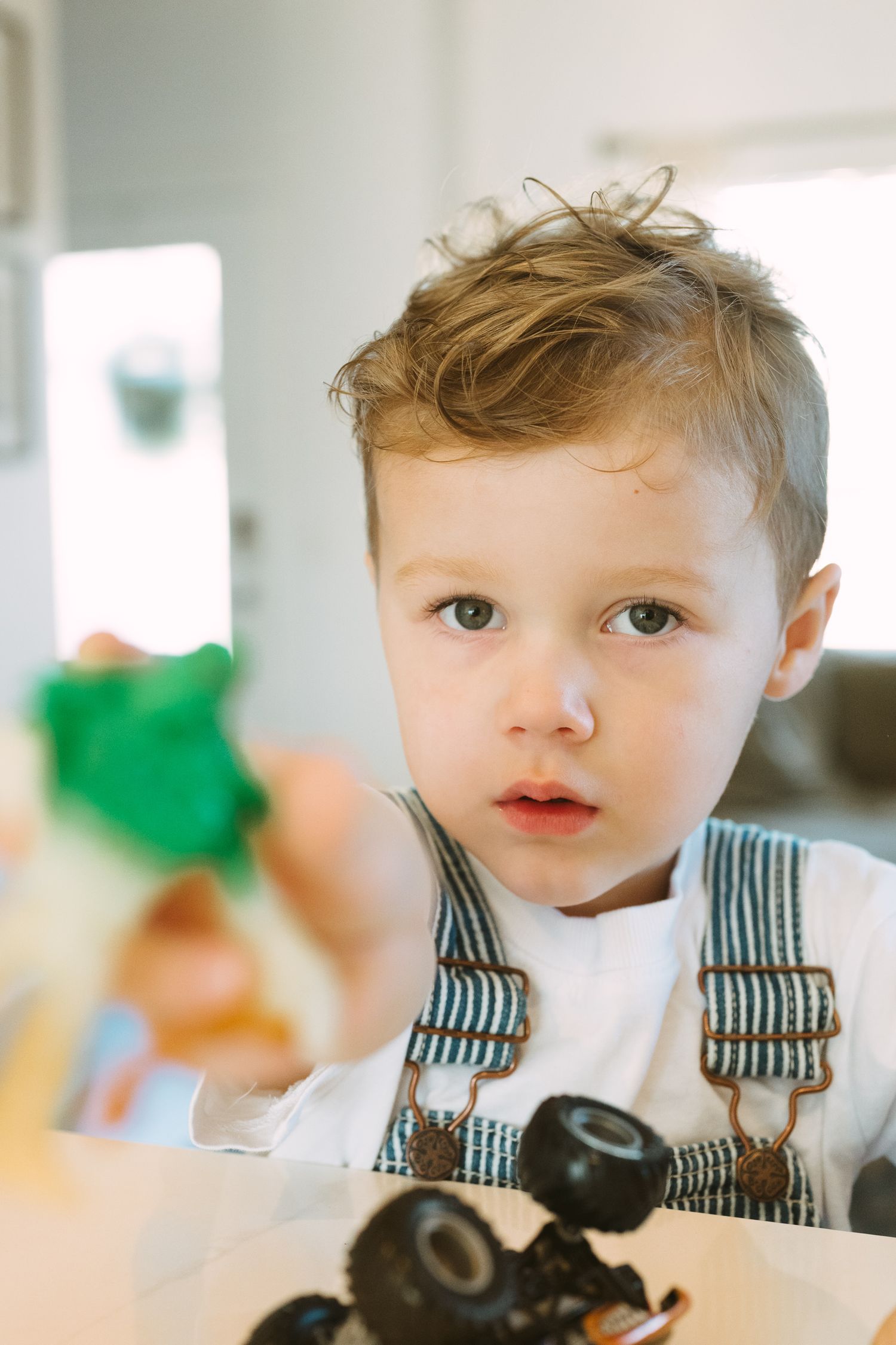 Close up shots of a young child playing with toy cars on a light colored surface.