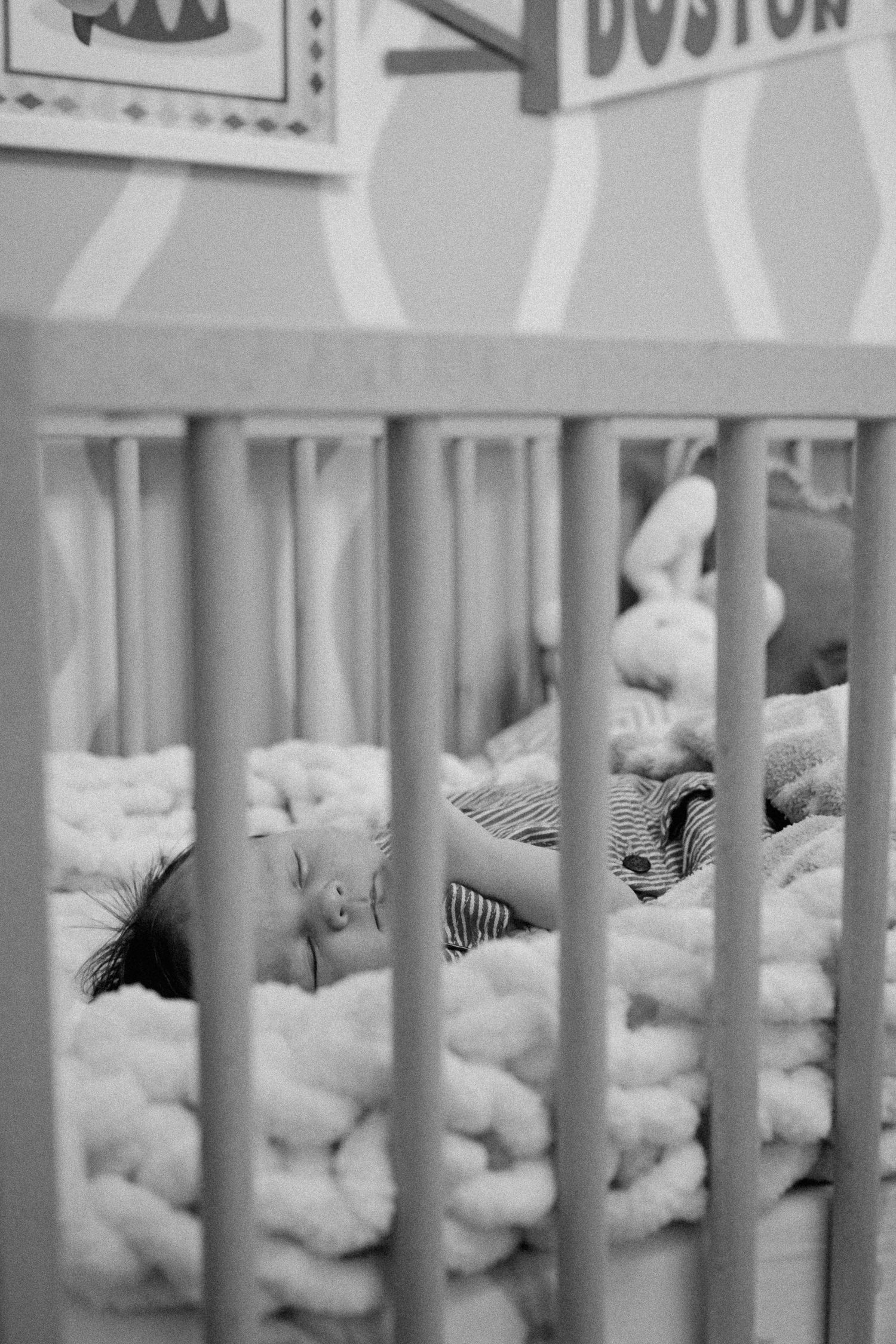 View through white crib bars showing bedding and decorative elements.