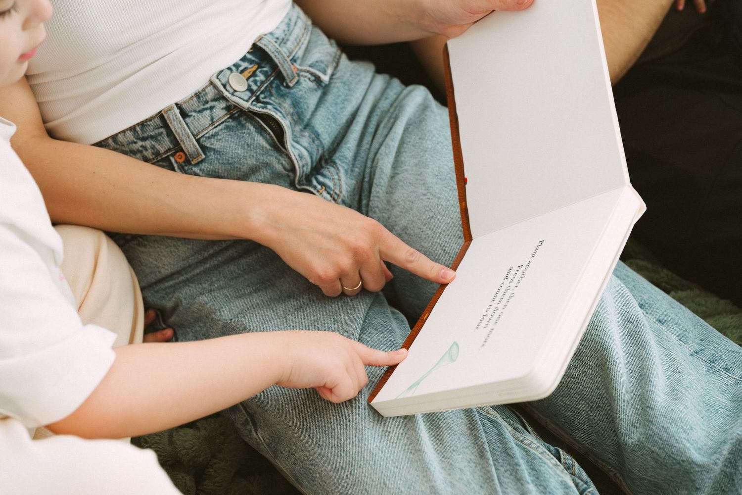 Someone reads a book while sitting comfortably on a couch in casual attire.