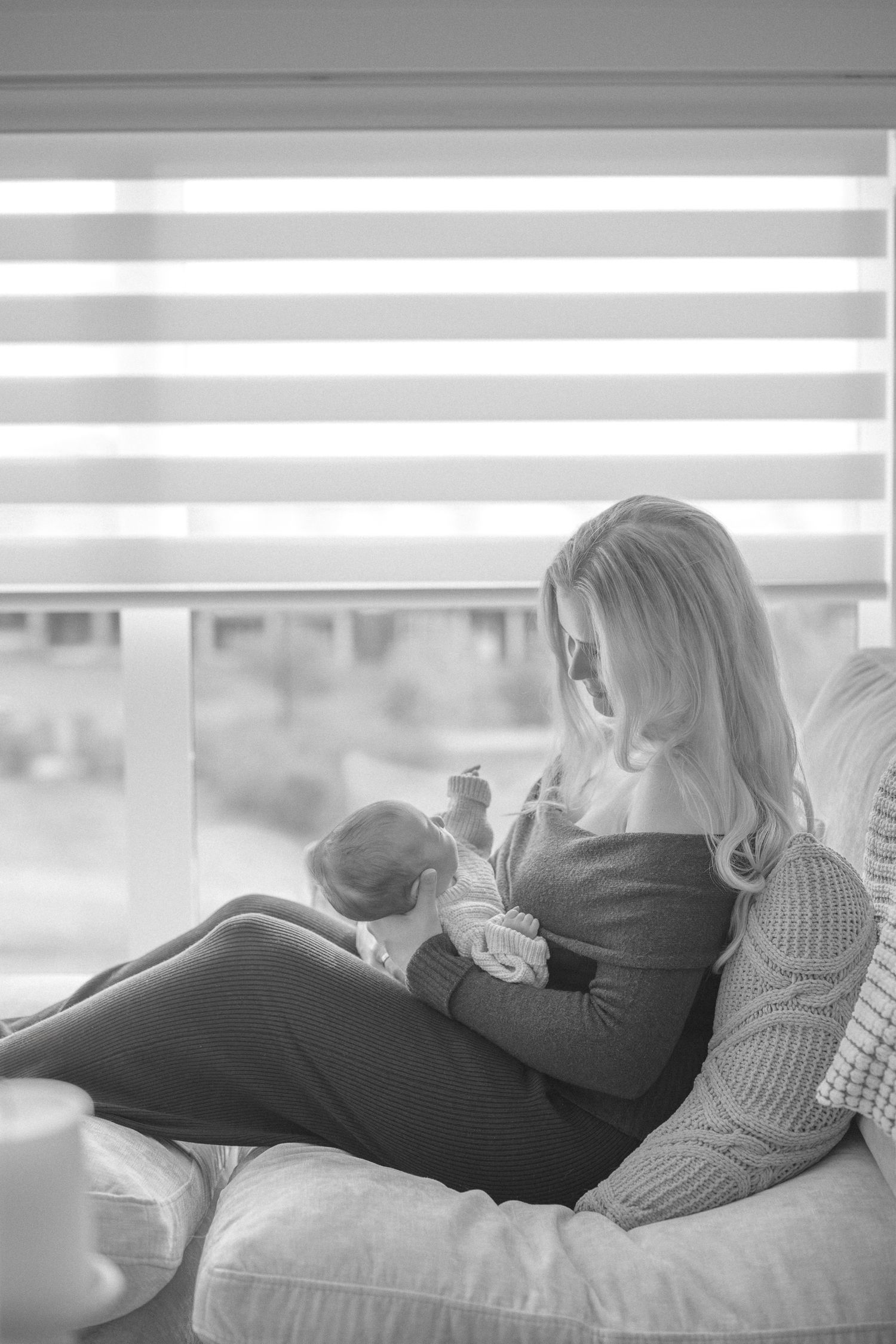 A tender moment captured in black and white showing intimate connection on a couch near a window.