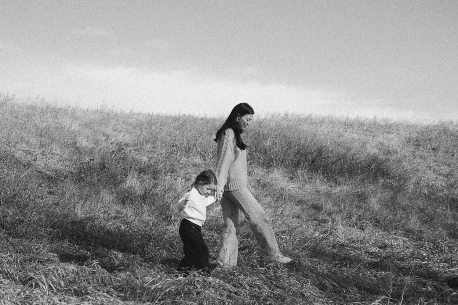 A black and white panoramic sequence shows a figure rolling down a grassy hillside in seven progressive frames.