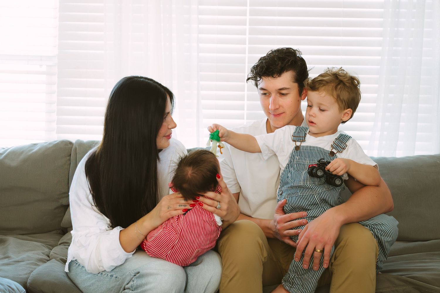 Family spending quality time together on couch while playing with toys and reading books at home.