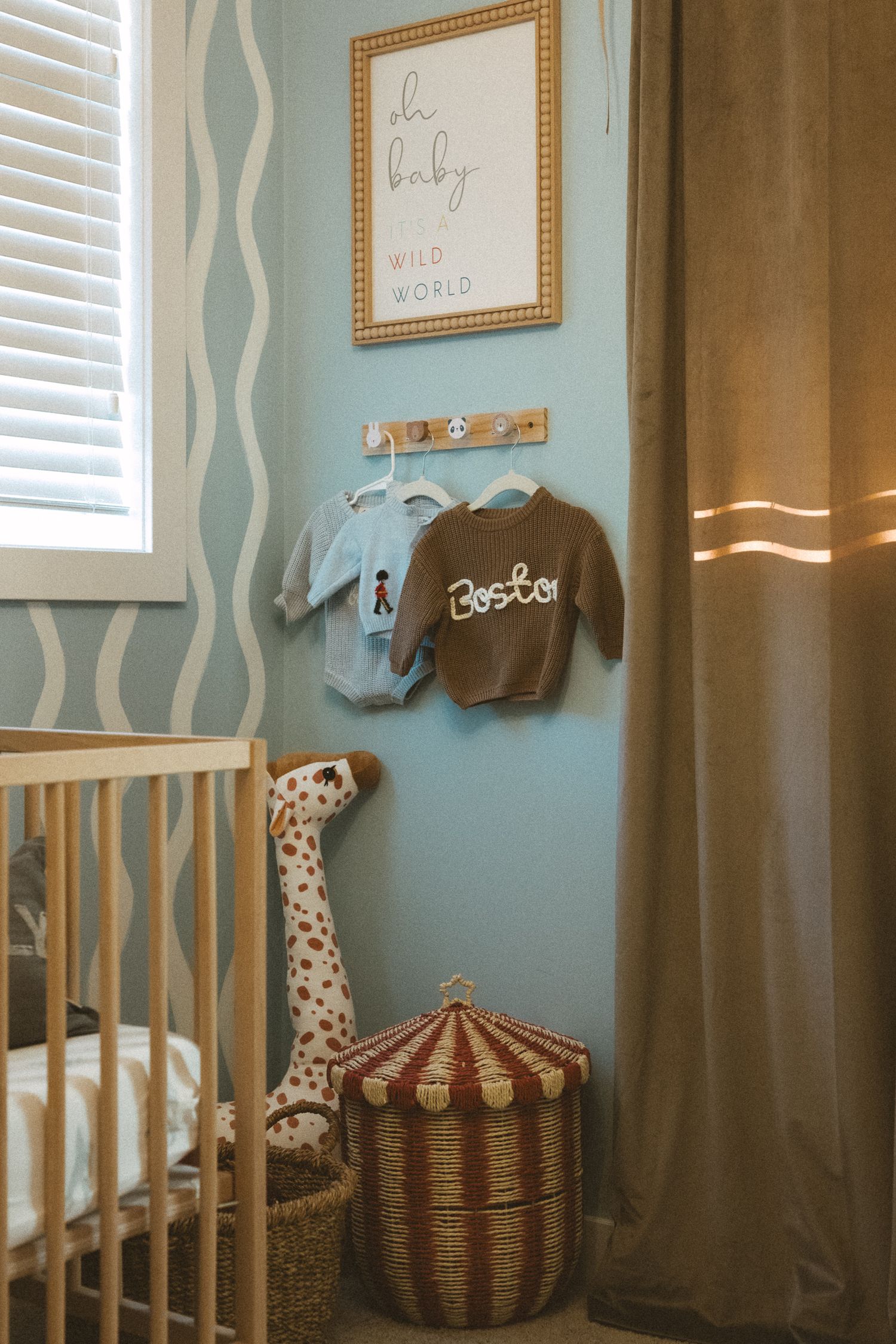 A nursery corner decorated in soft blue tones with a crib, stuffed animals, and framed artwork on the walls.