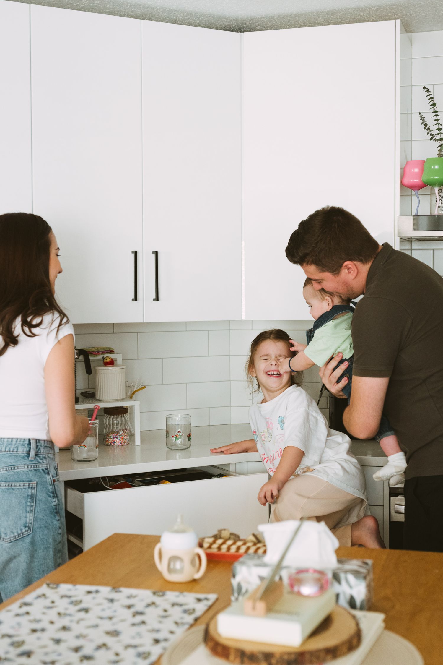 A heartwarming kitchen scene shows a family gathered around a wooden table sharing joyful moments together.