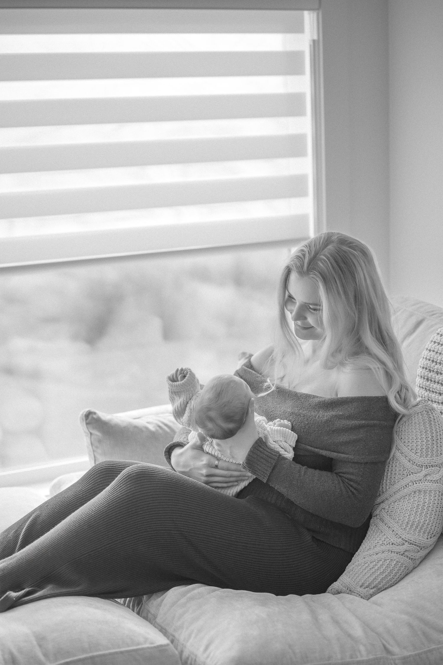 Intimate black and white photograph of figures resting together by a window with natural light.