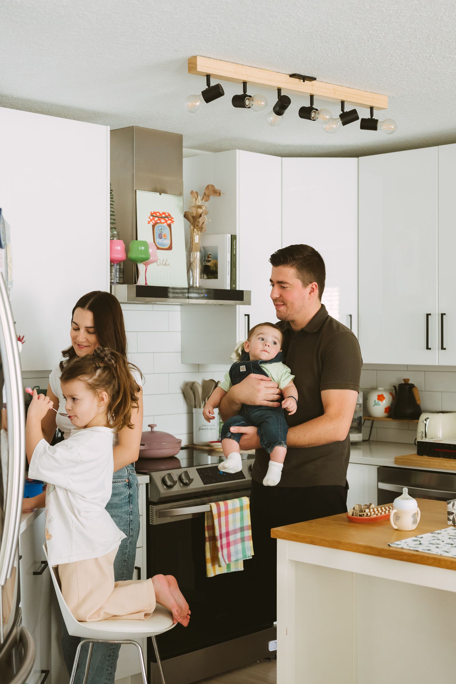 Modern white kitchen scene showing family interaction and daily activities.